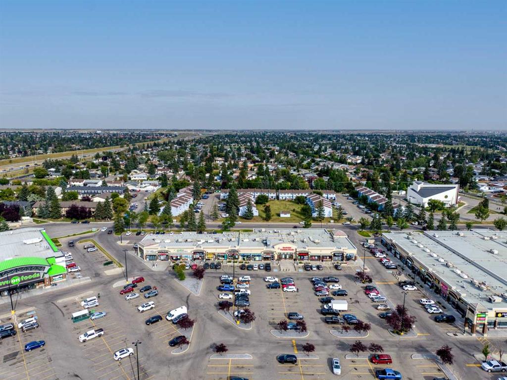 Aerial view of a shopping plaza, parking lots, and surrounding Calgary neighborhood.