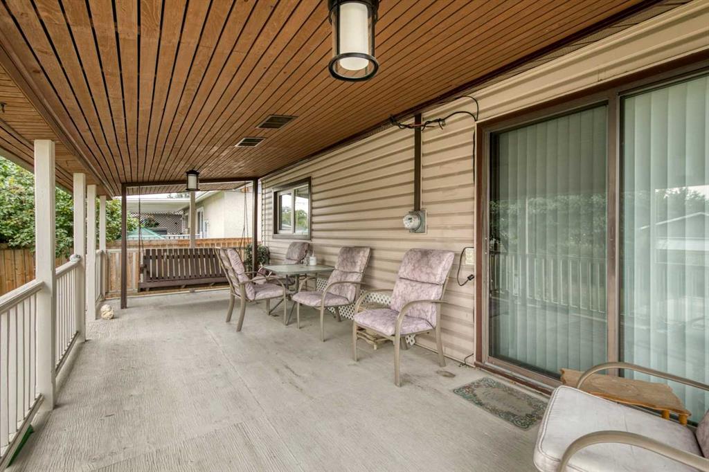 Covered patio with a wood-plank ceiling, sliding glass doors, and cushioned seating.