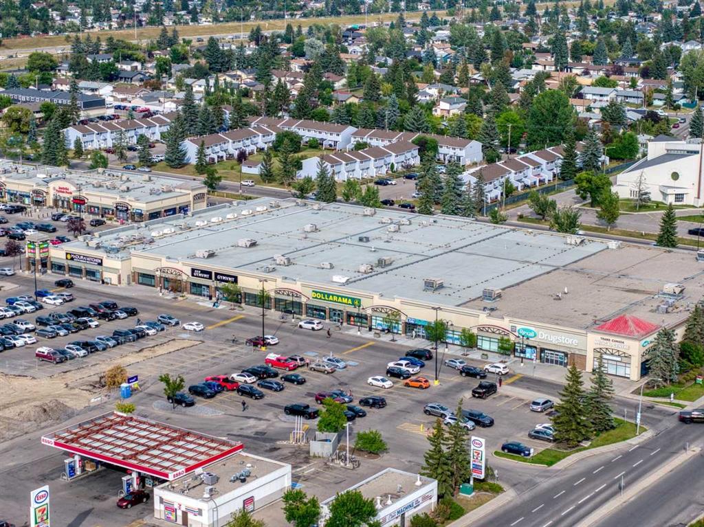 Aerial view of a shopping plaza, gas station, and nearby townhouses.
