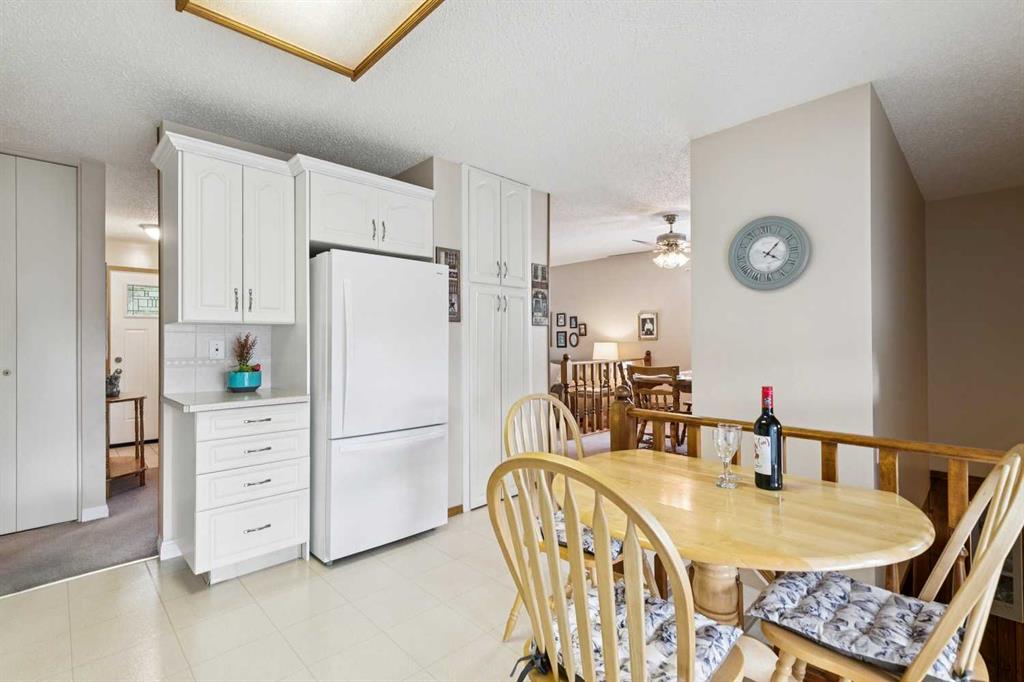 Kitchen and dining area with white cabinetry, a large refrigerator, and a round wooden dining table.