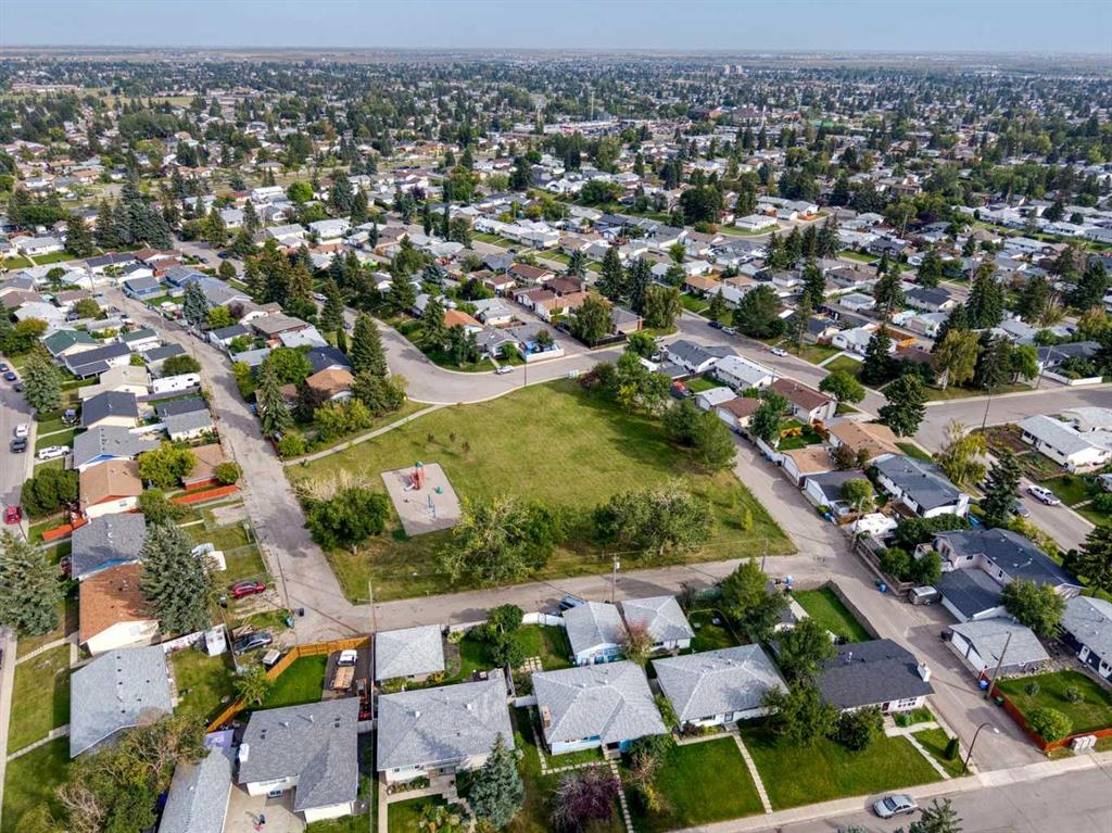 Aerial view of a residential neighborhood surrounding a grassy open lot and playground.