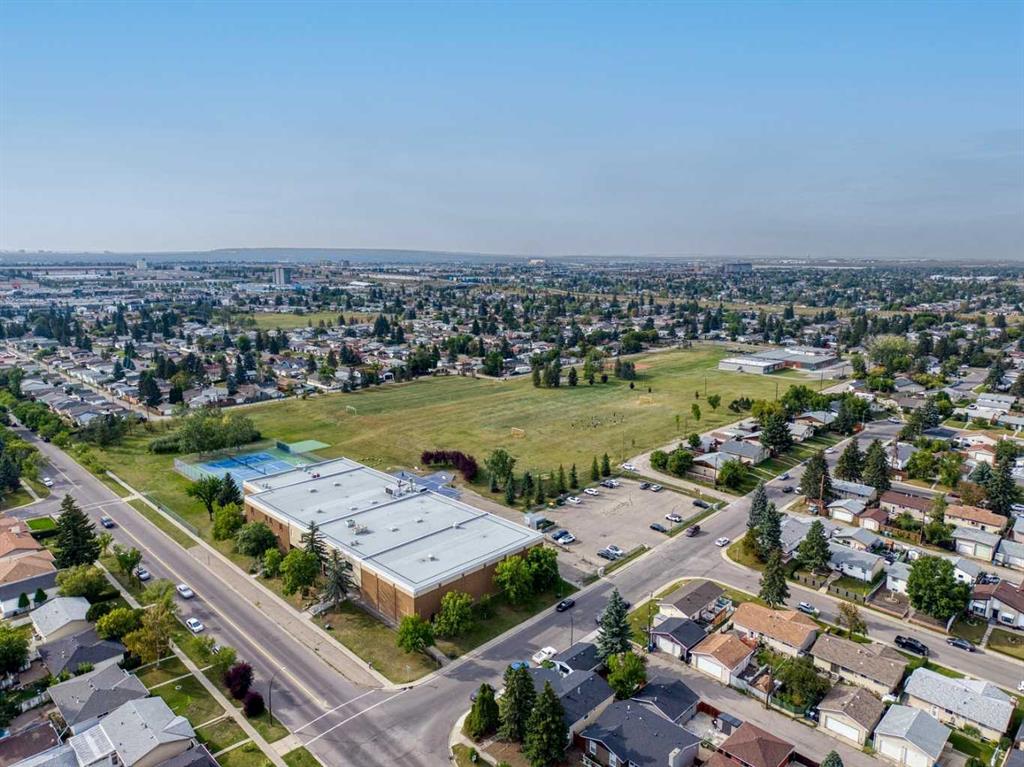 Aerial view of a neighborhood, open green field, and low-rise commercial building.