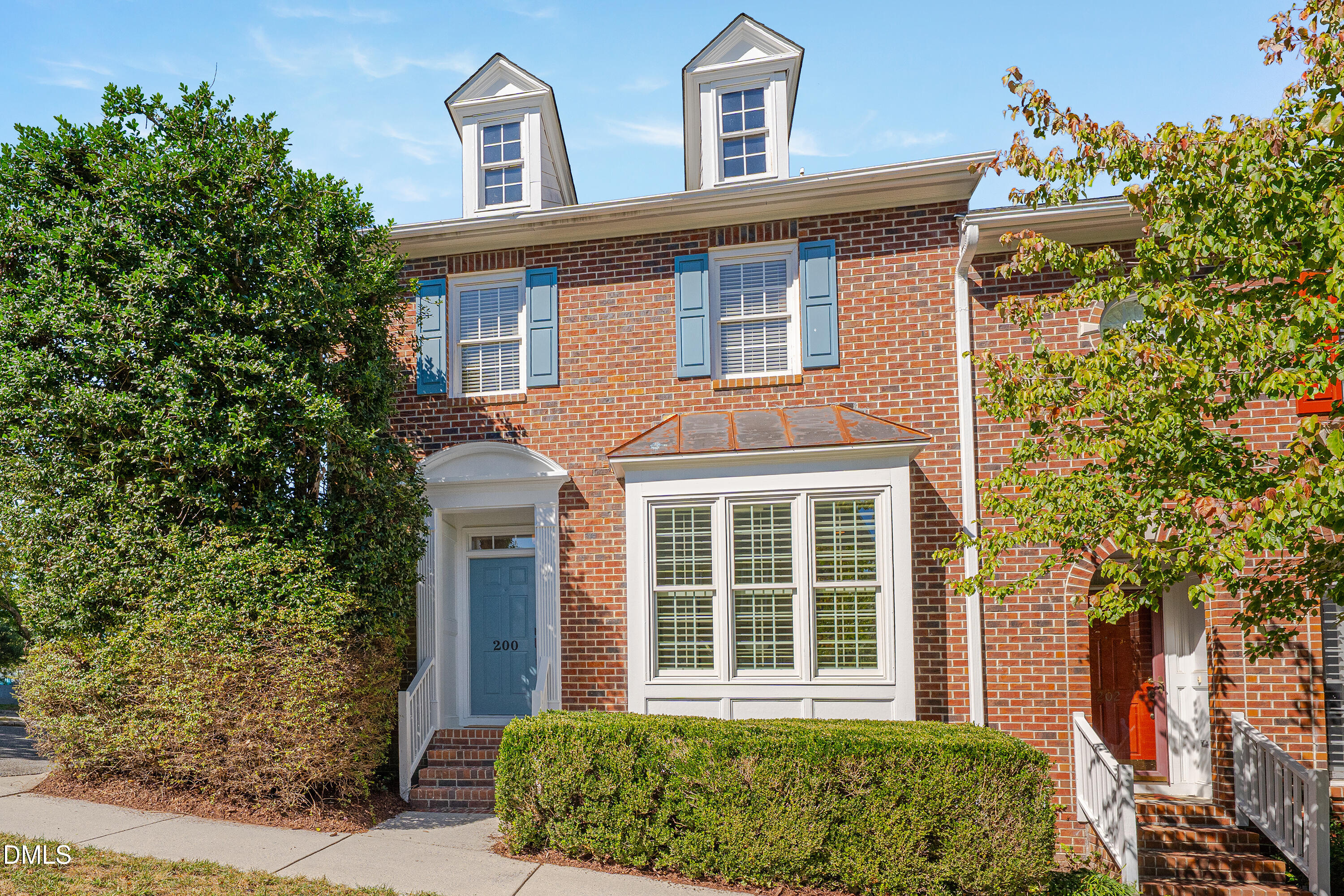 Red-brick townhouses with blue shutters, roof dormers, and doors numbered 200 and 202.