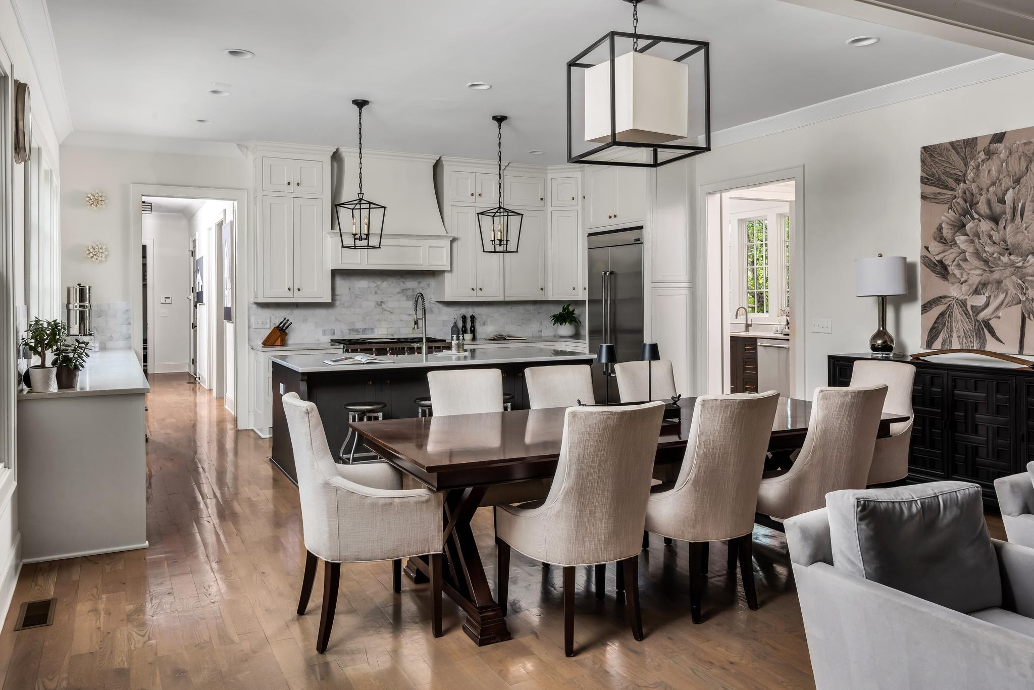 Open kitchen and dining area with a large island, white cabinetry, and hardwood floors.