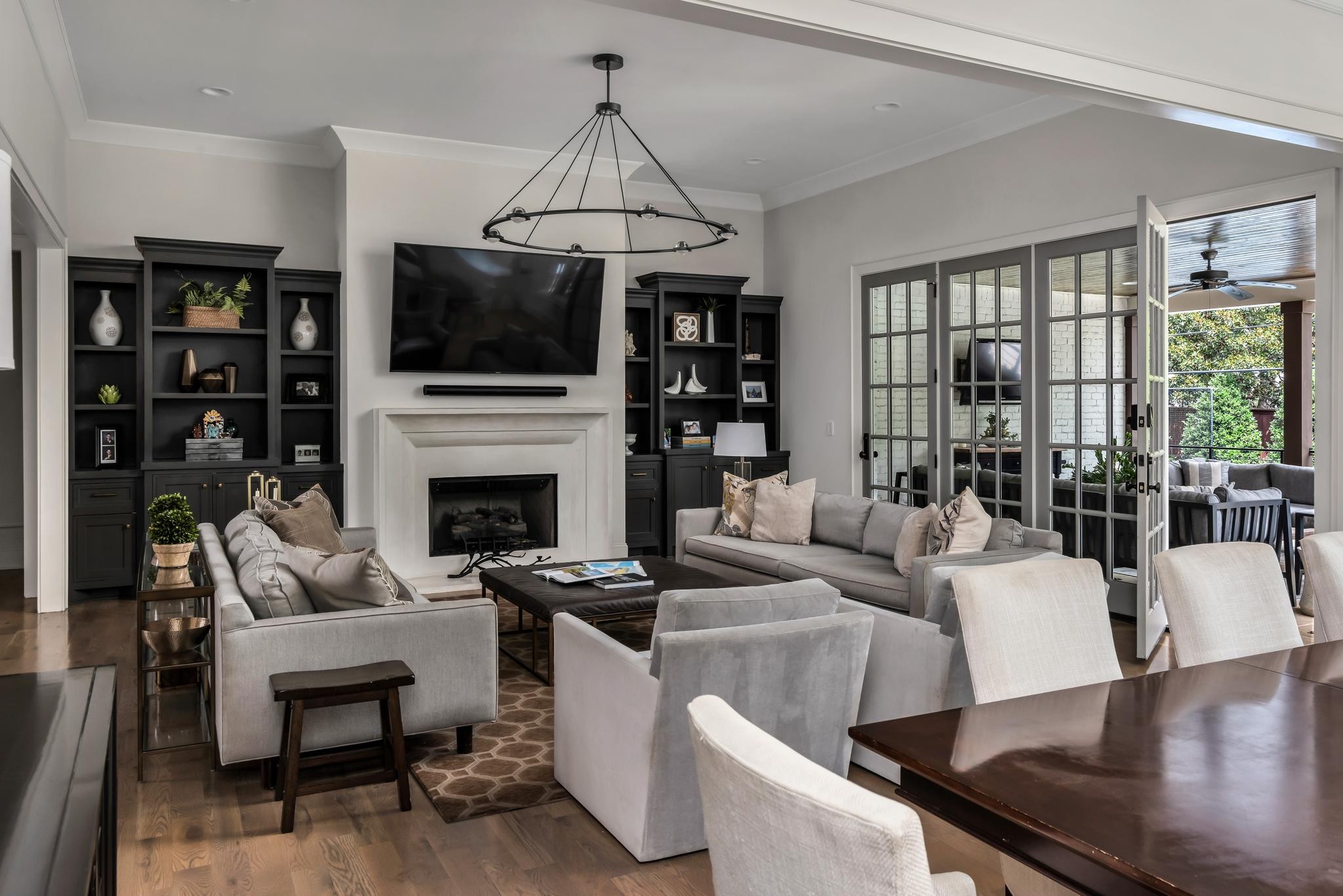 Living room with a fireplace, dark built-in shelves, and open French doors to a covered patio.
