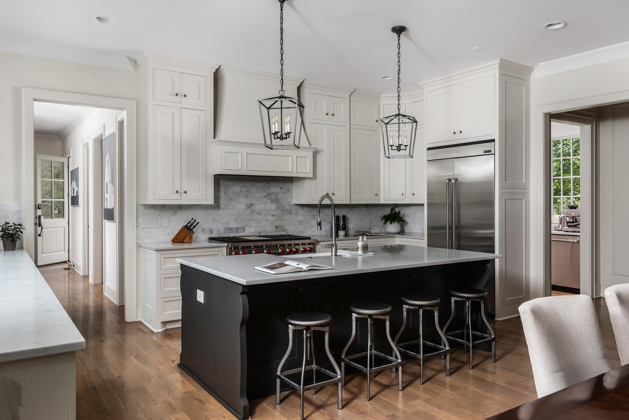 Kitchen with white cabinetry, marble surfaces, and a large dark island with bar stools.