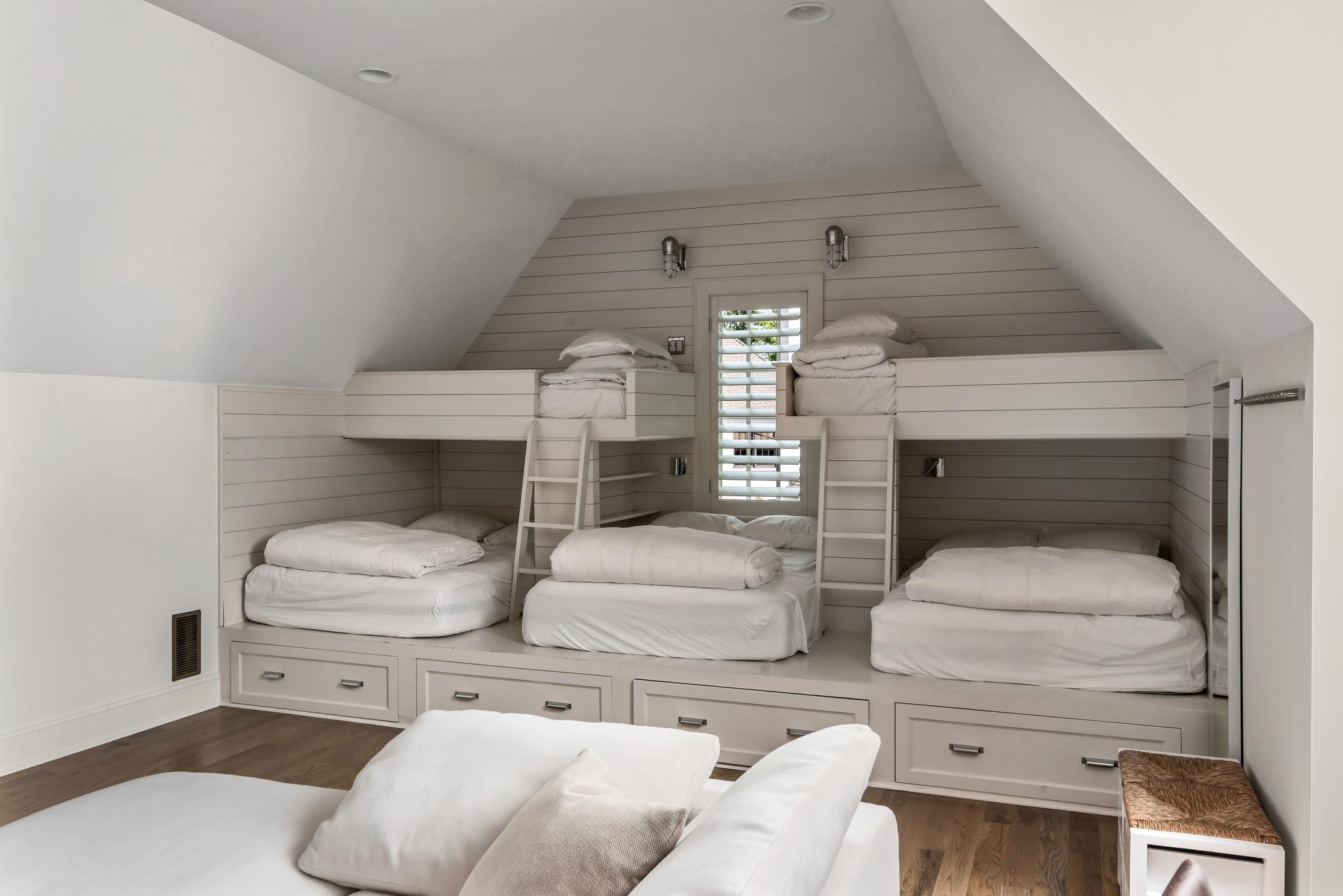 Attic bedroom with built-in bunk beds, ladders, and storage drawers.