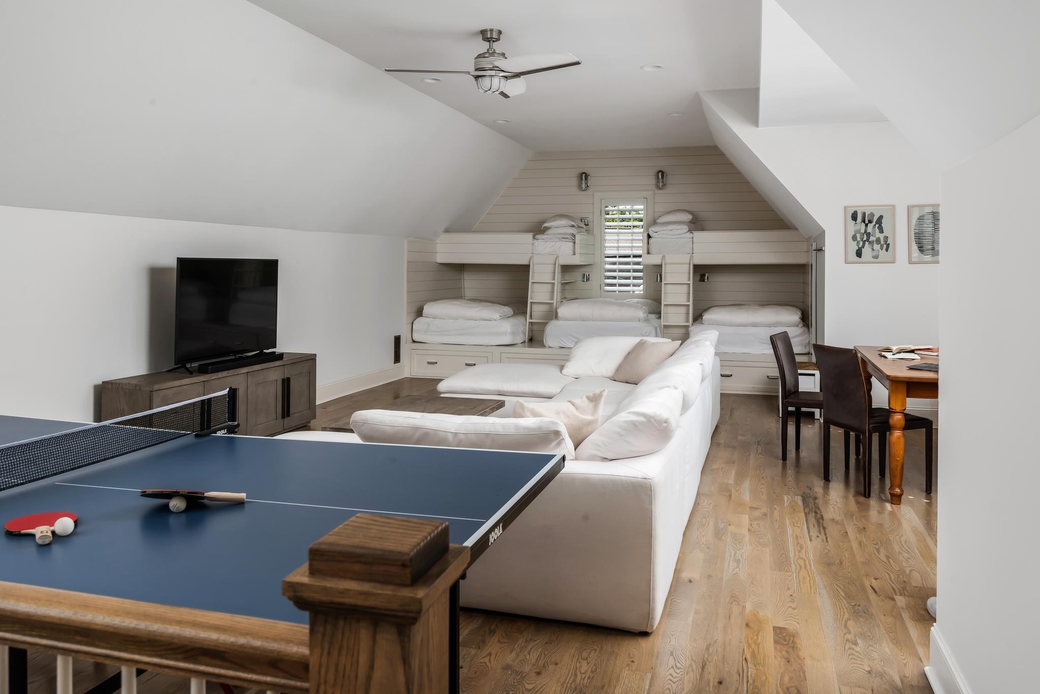 Bonus room with built-in bunk beds, a white sectional sofa, and a ping-pong table.