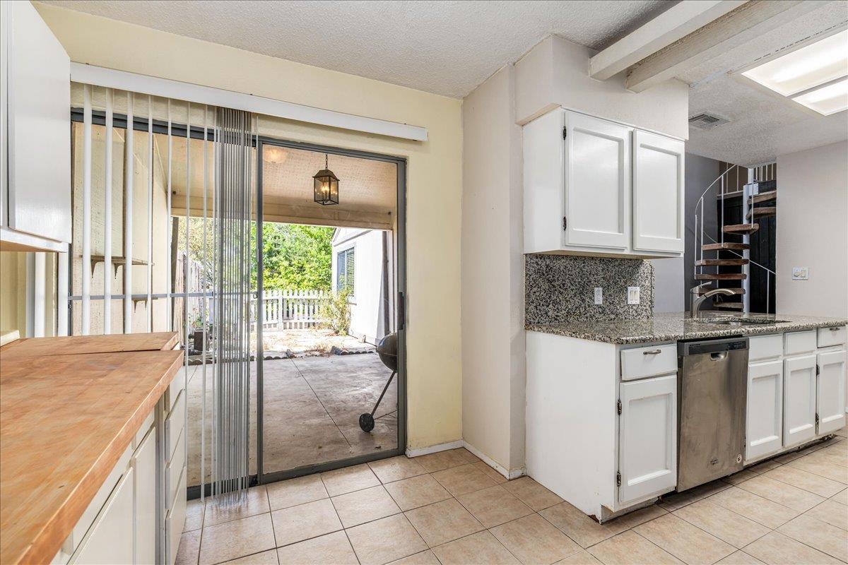 Kitchen with granite counters and a sliding glass door opening to a covered patio.