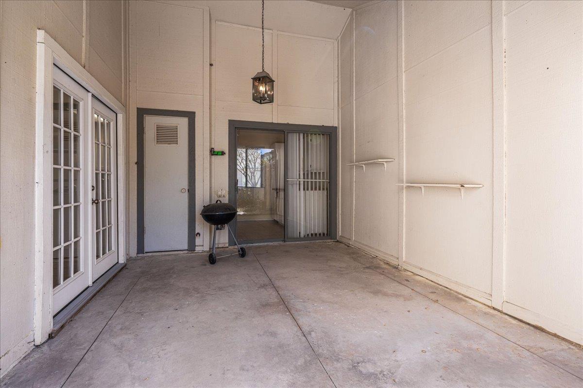 Covered patio with French doors, a sliding glass door, and a small charcoal grill.