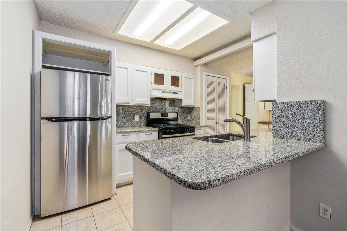 Kitchen with granite peninsula, undermount sink, white cabinets, and stainless steel appliances.
