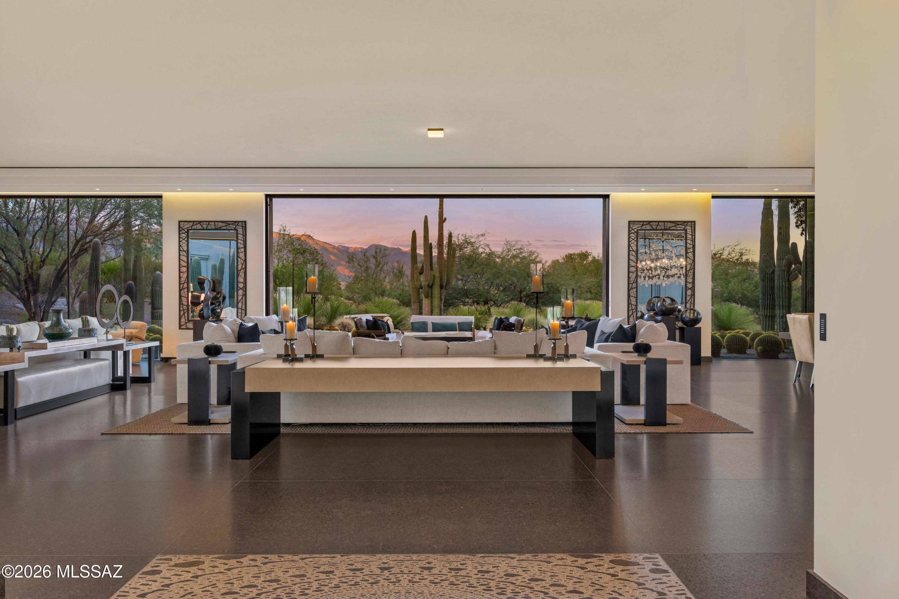 Modern living room with wide windows framing saguaro cacti and mountains at dusk.
