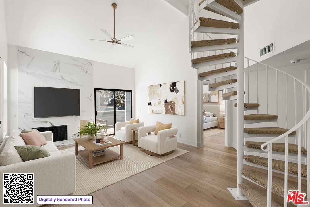 Staged living room with a marble fireplace wall and a carpeted spiral staircase.