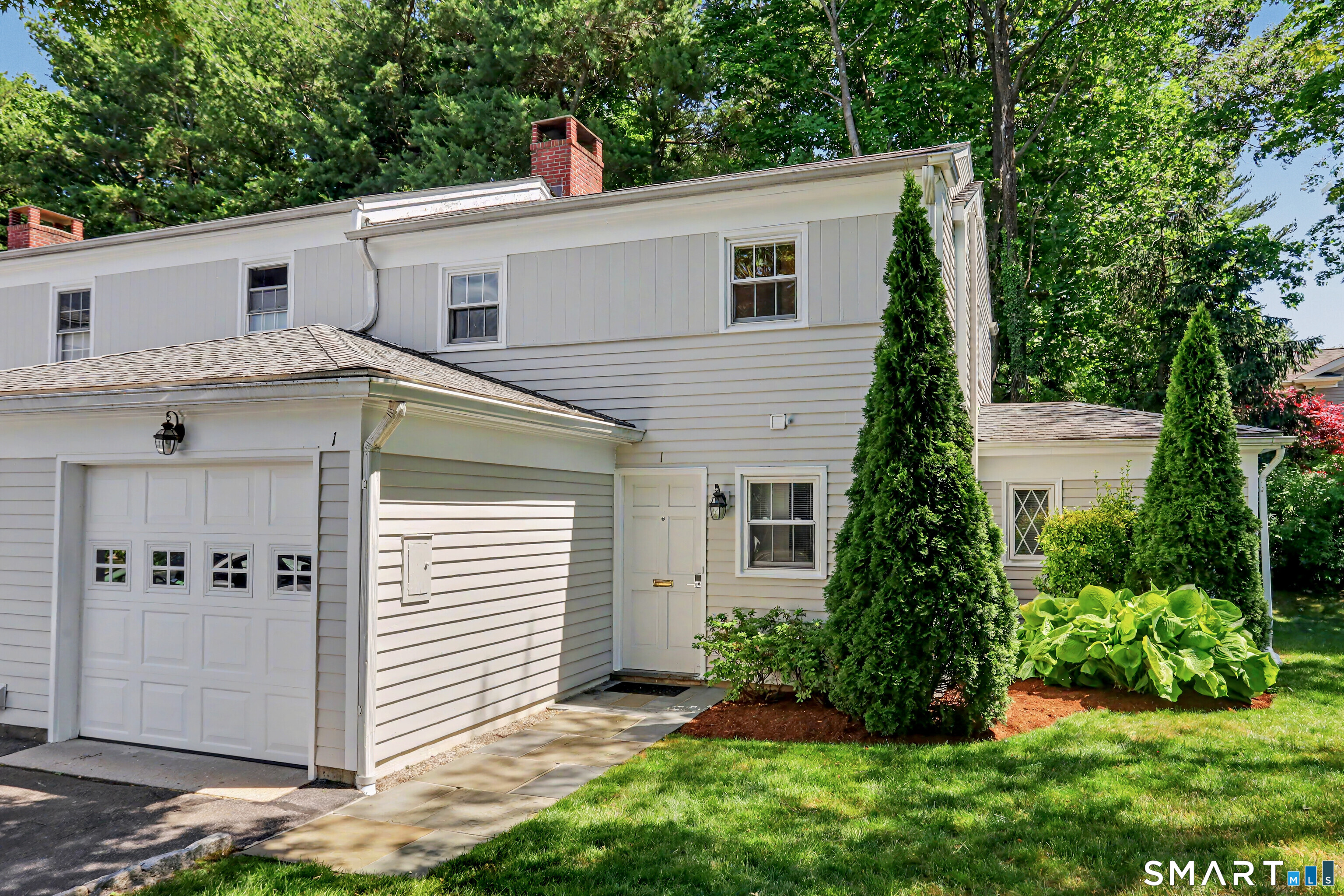 White-sided home with an attached garage, side entrance, and landscaped lawn.