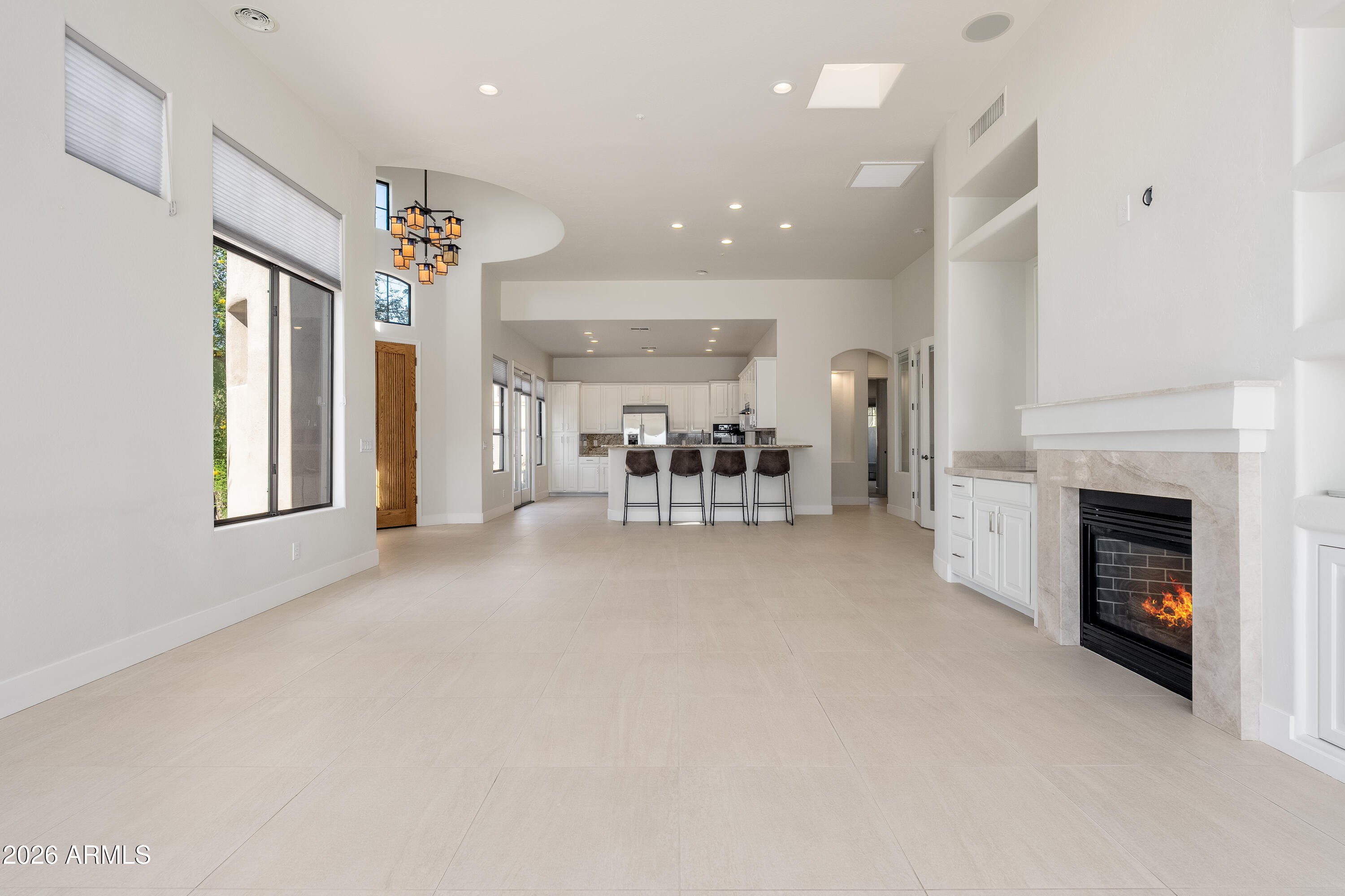 Open living room and kitchen with a stone-surround fireplace and four stools at the island.