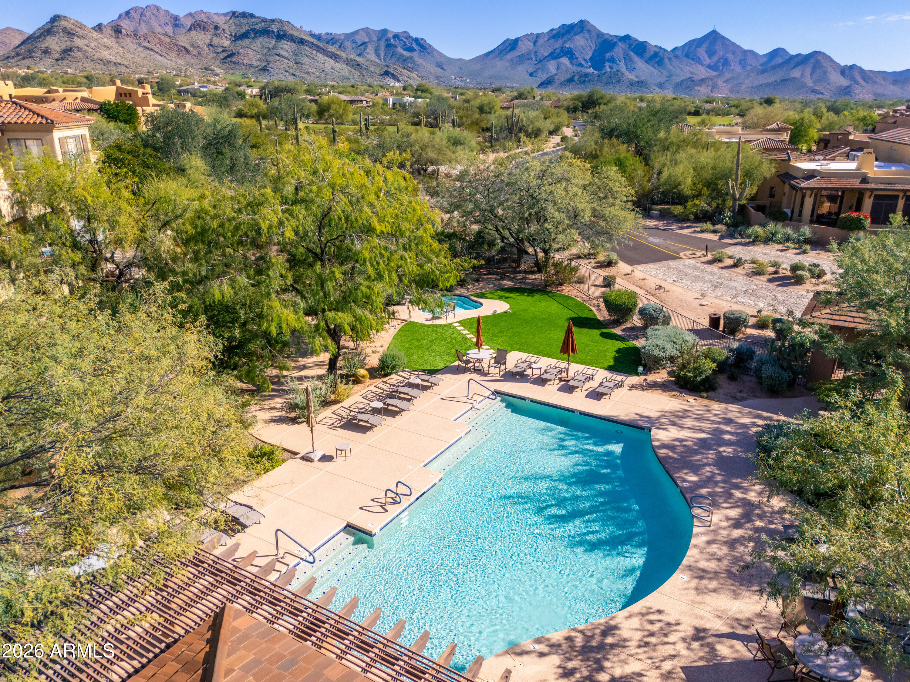 Community pool with lounge chairs and desert mountains in the background.