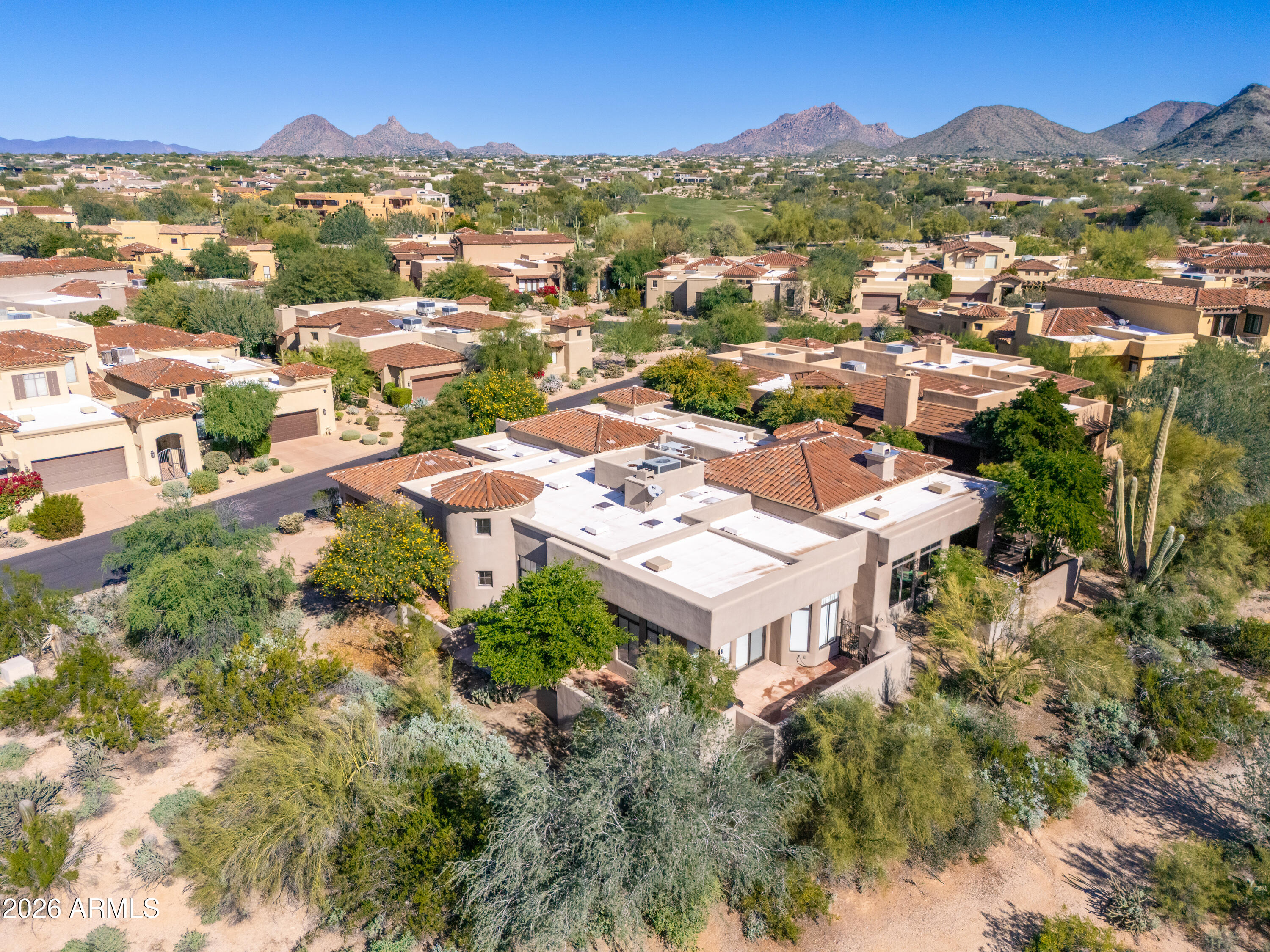 Scottsdale home with tile roofs and desert landscaping, backed by mountains and a golf course.