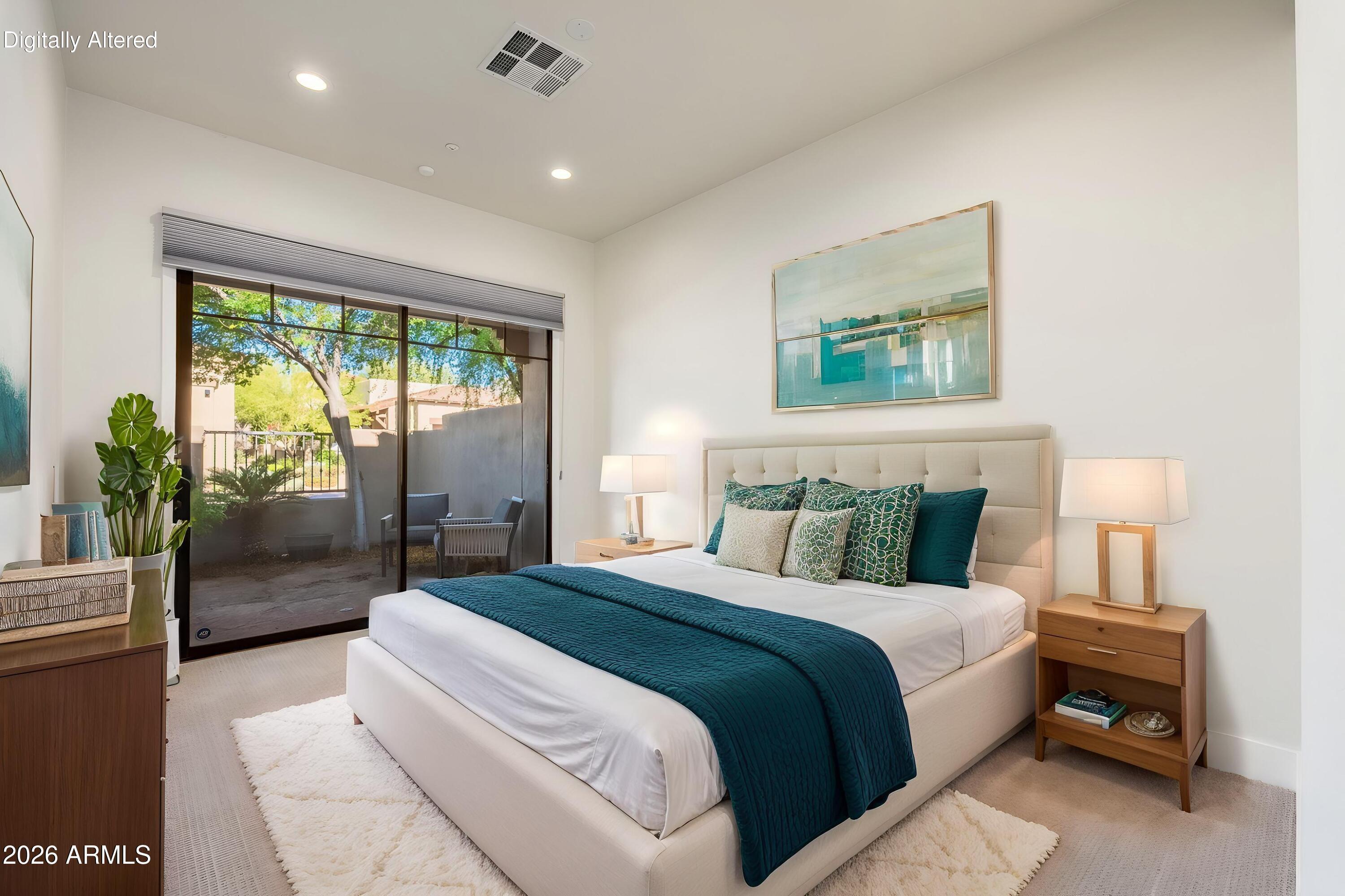 Furnished bedroom with a cream bed, teal bedding accents, and sliding glass doors to a patio.