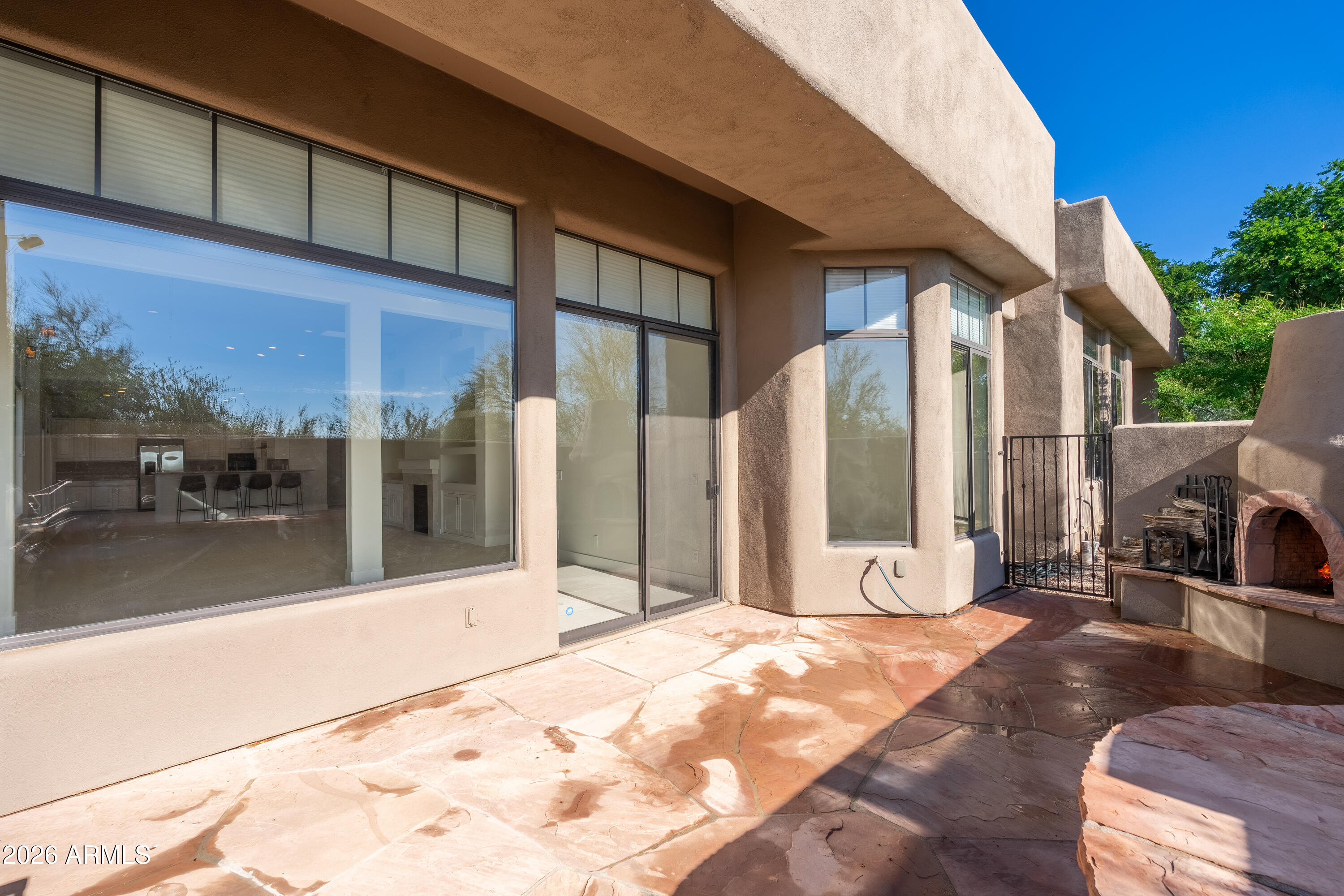 Stone patio with large sliding glass doors and a built-in outdoor fireplace.