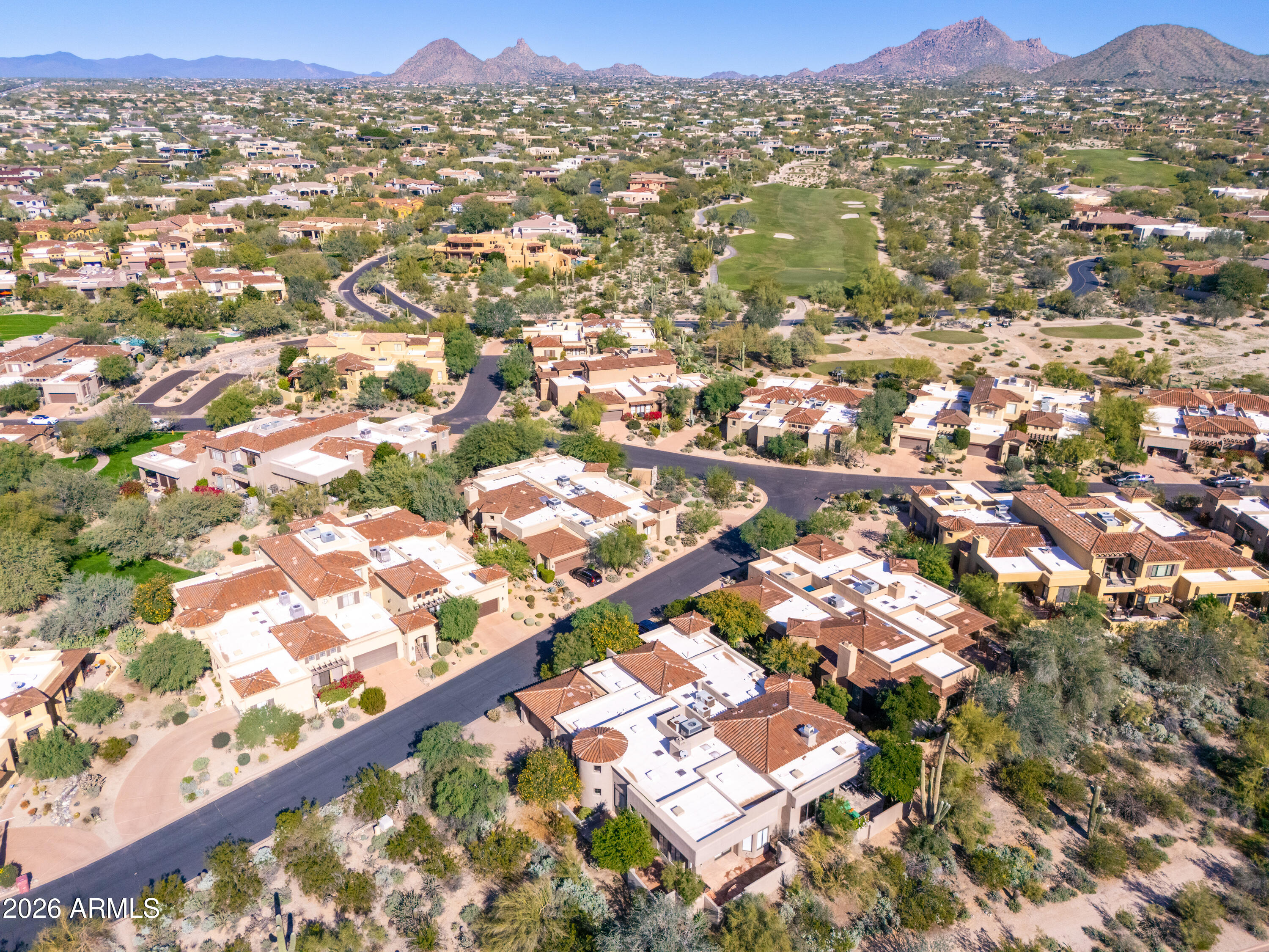 Scottsdale homes surrounded by desert landscaping, with a golf course and mountains beyond.