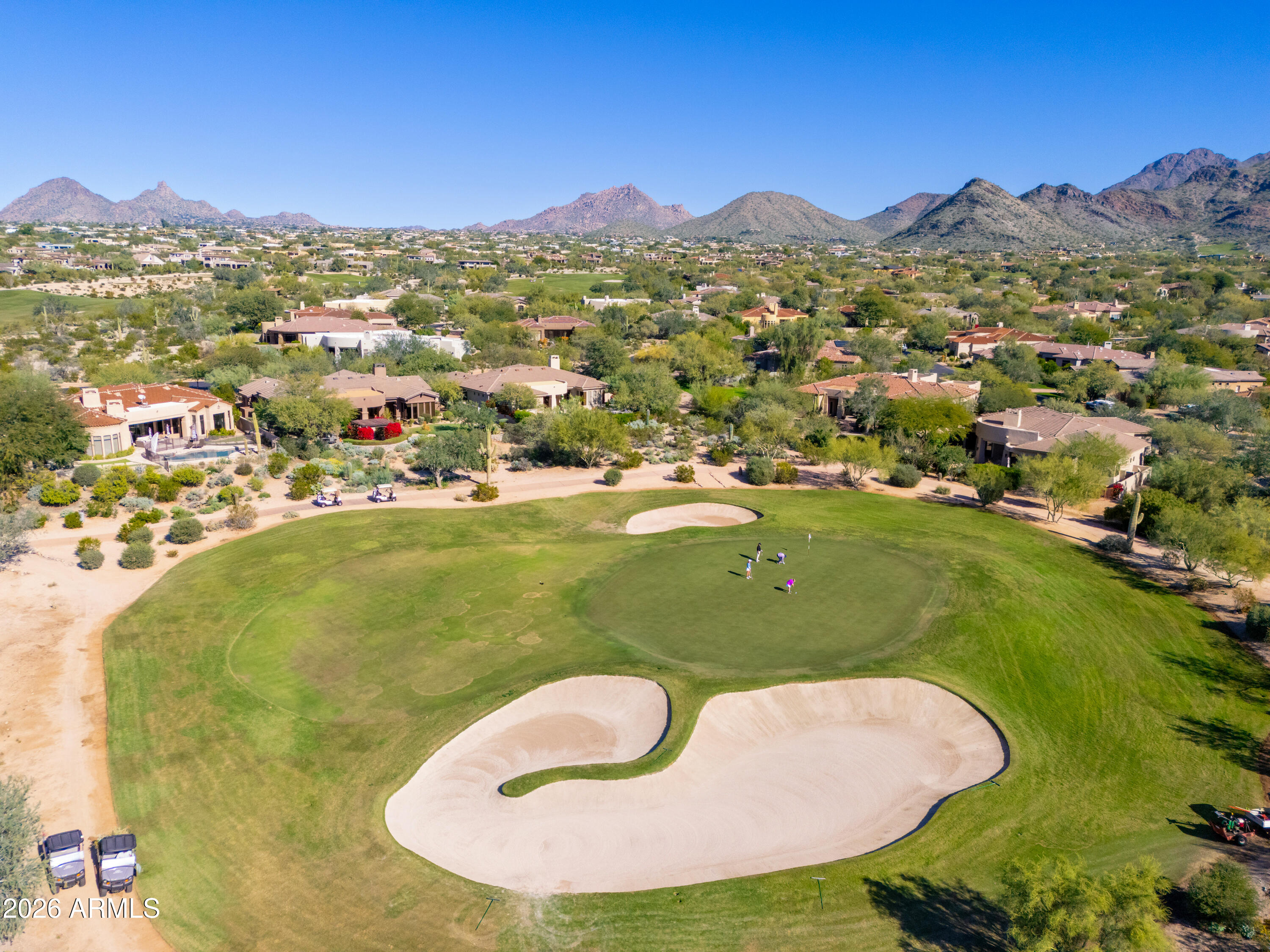 Golf course green and sand bunker, with Scottsdale homes and desert mountains beyond.