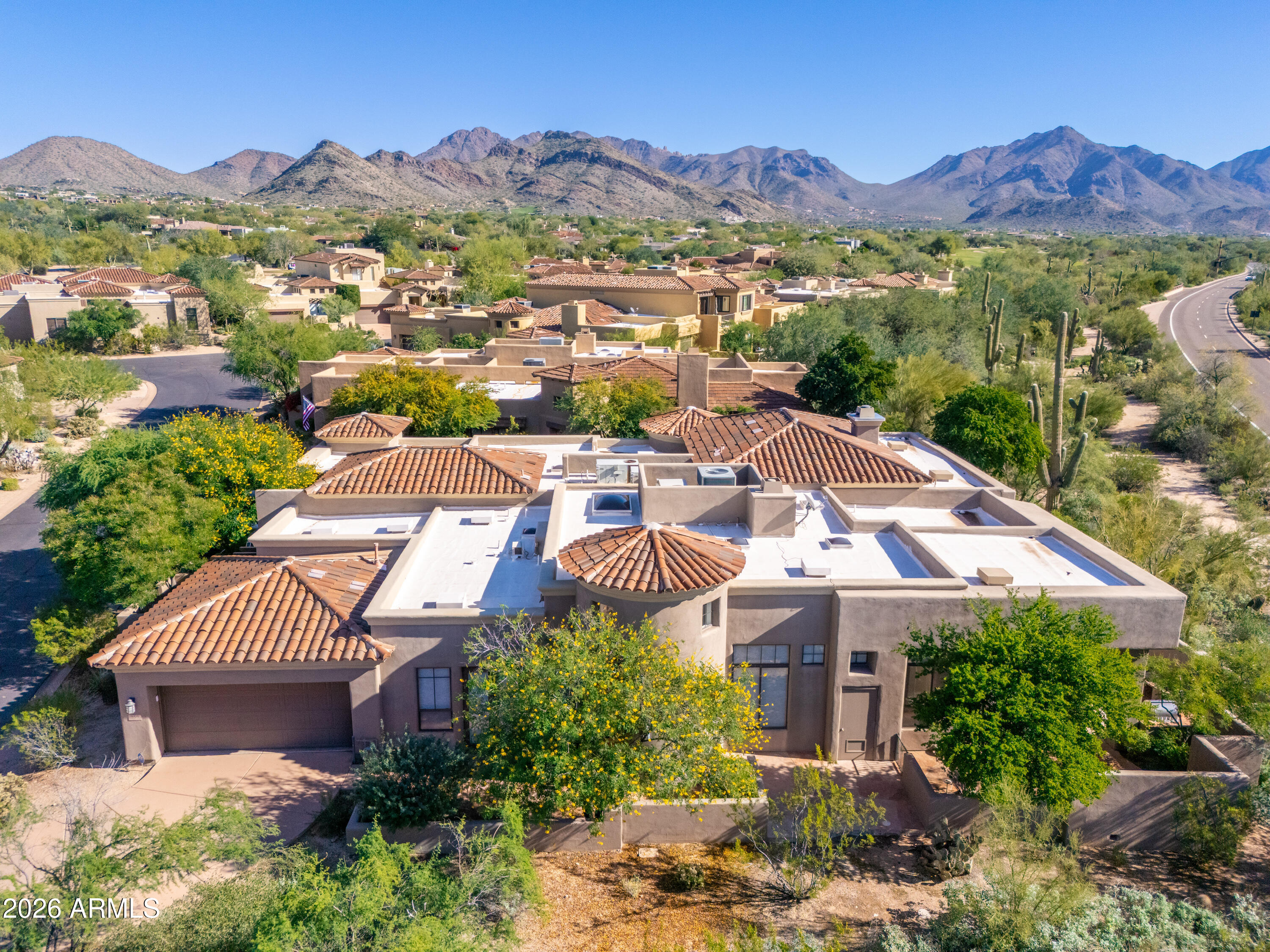 Aerial view of a tile-roofed Scottsdale home, with desert landscaping and mountains beyond.