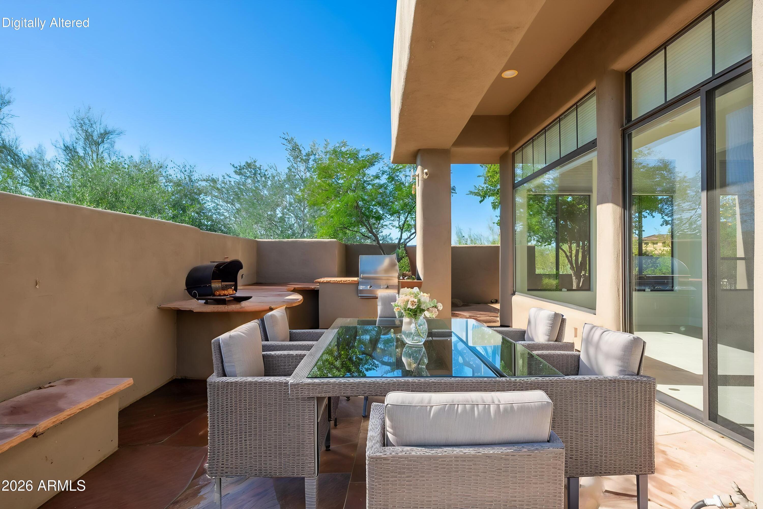 Covered patio with wicker dining set, built-in grills, and large sliding glass doors.