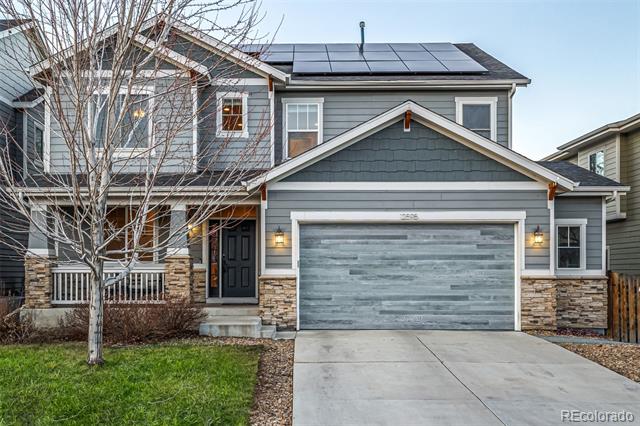 Two-story gray house with stone veneer, rooftop solar panels, and a wide garage.