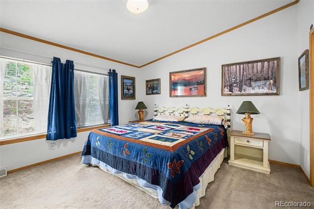 Bedroom with a colorful patchwork quilt, blue window curtains, and matching bedside tables.