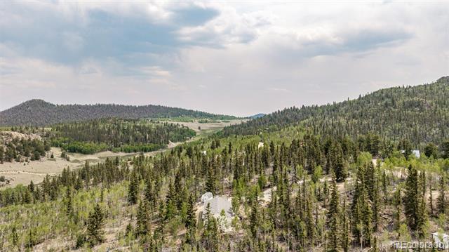 Aerial view of a wooded mountain valley with scattered homes and distant ridgelines.