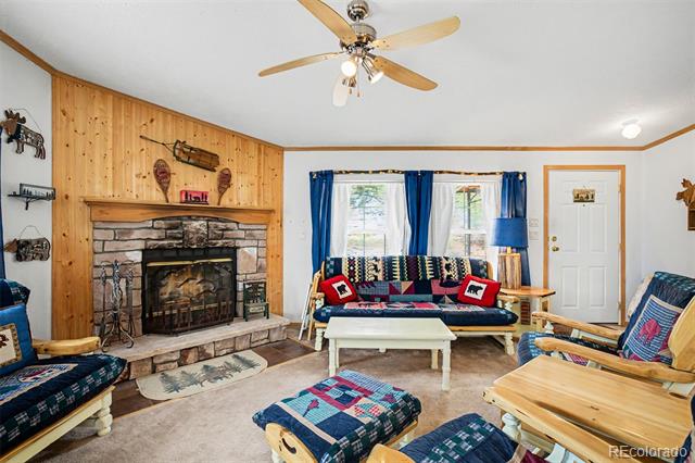 Living room with a stone fireplace, wood-paneled wall, and blue patterned seating.