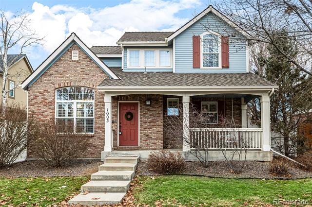 Two-story brick and blue-sided home with a red front door and covered porch.