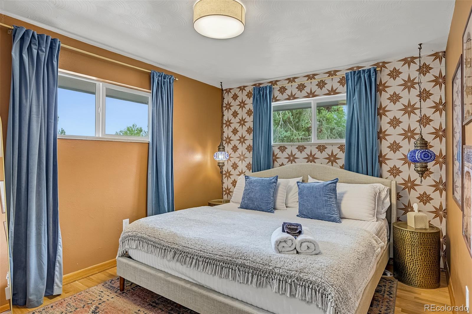 Staged bedroom with a large bed, blue curtains, and a geometric star-patterned accent wall.