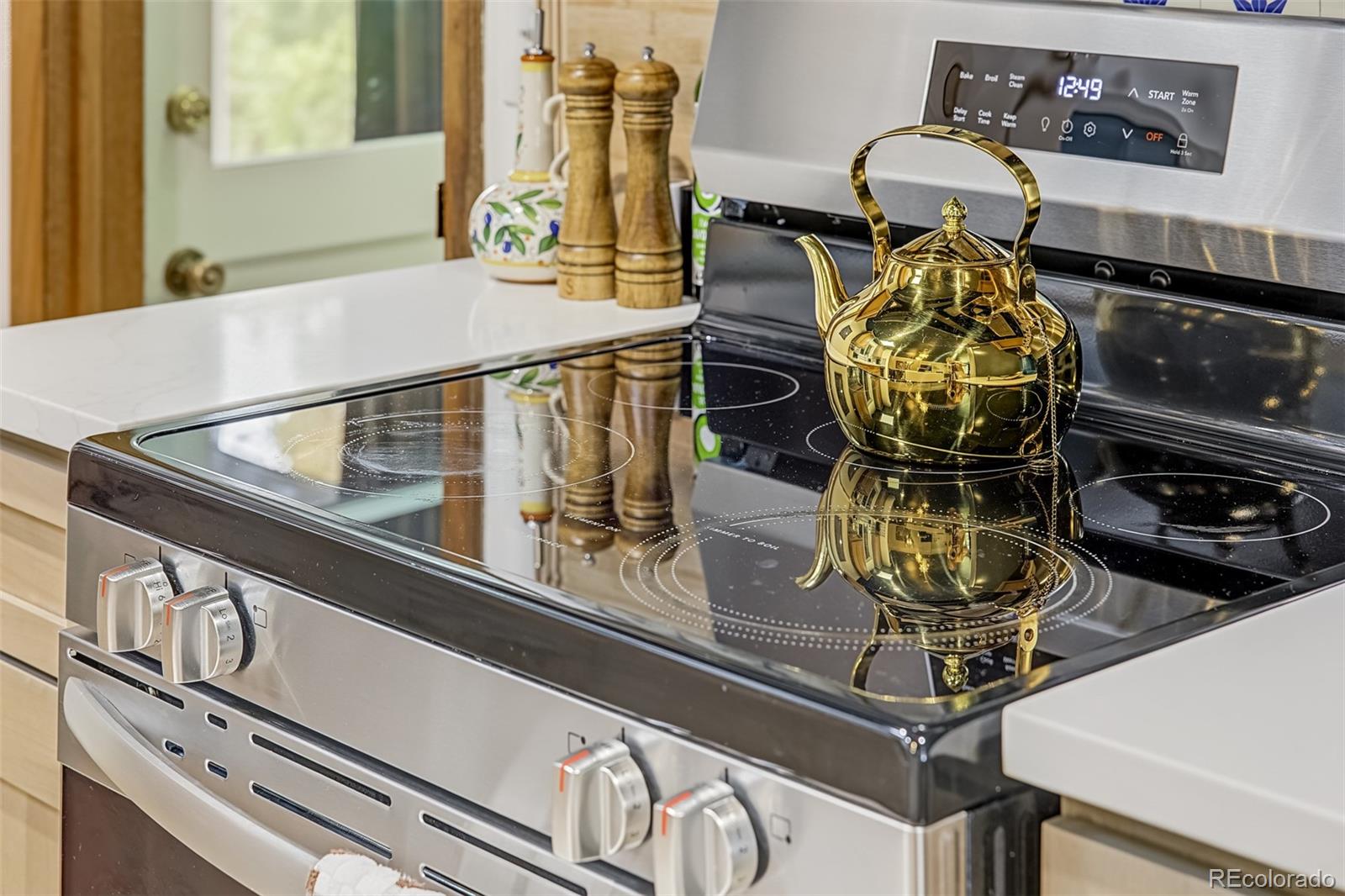 Kitchen range with a black glass cooktop and reflective gold kettle.