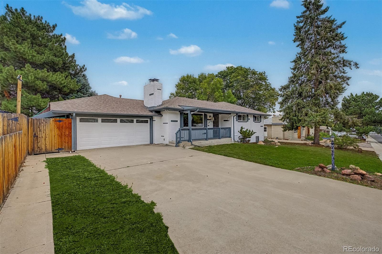 Single-story white brick home with a two-car garage, covered porch, and broad driveway.