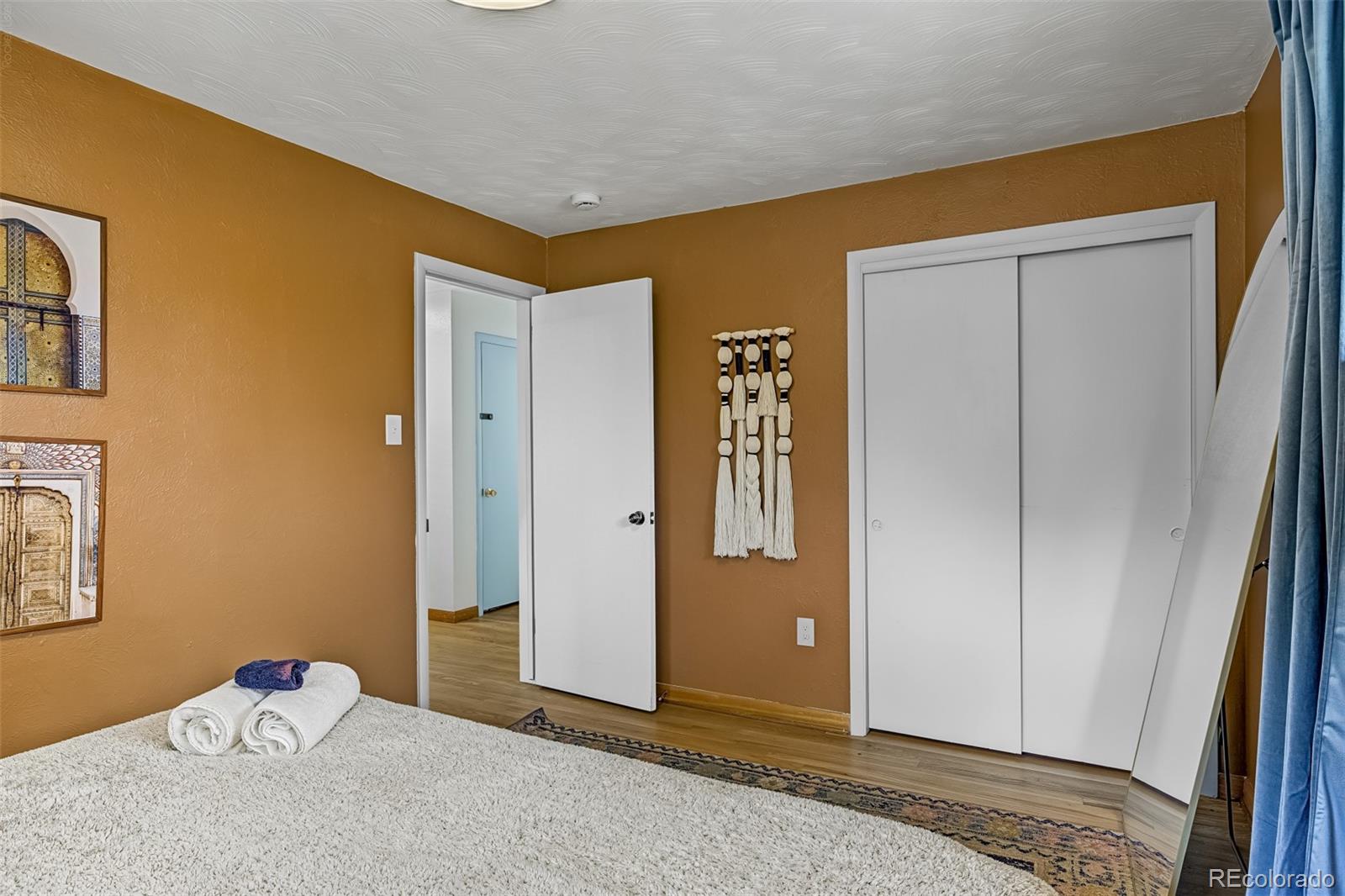 Bedroom with ochre walls, white carpet, sliding closet doors, and a full-length mirror.
