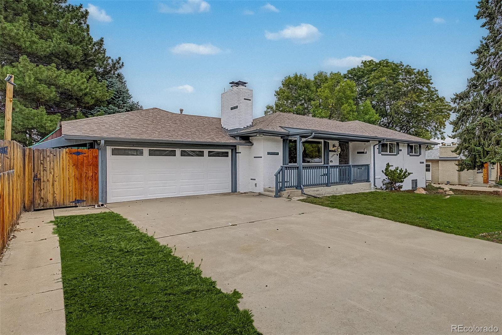 Single-story white-brick house with a two-car garage, covered porch, and broad driveway.