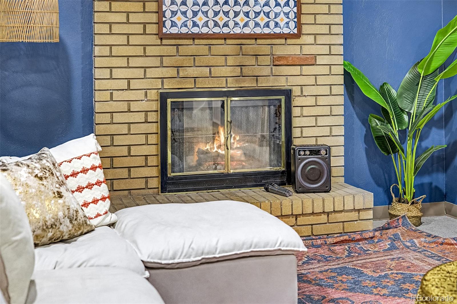 Living room with a brick fireplace, white sofa, blue walls, and patterned rug.