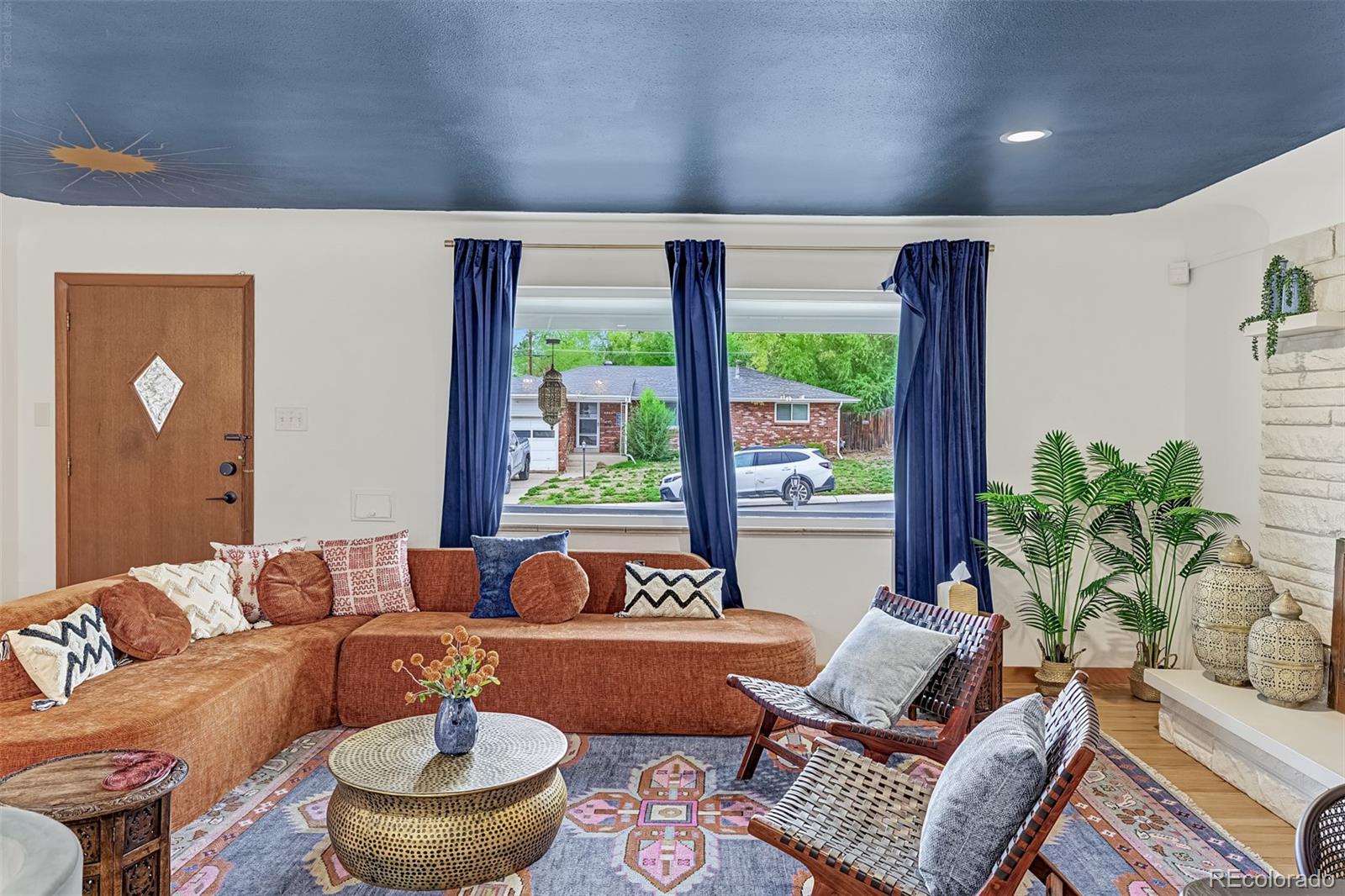 Living room with a rust-colored sectional, patterned rug, and blue ceiling featuring a sun motif.