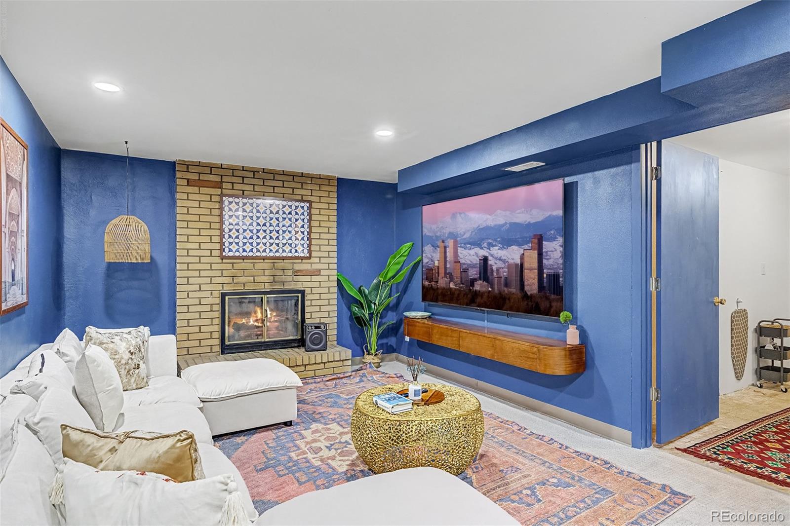 Living room with blue walls, a brick fireplace, white sectional, and patterned rug.