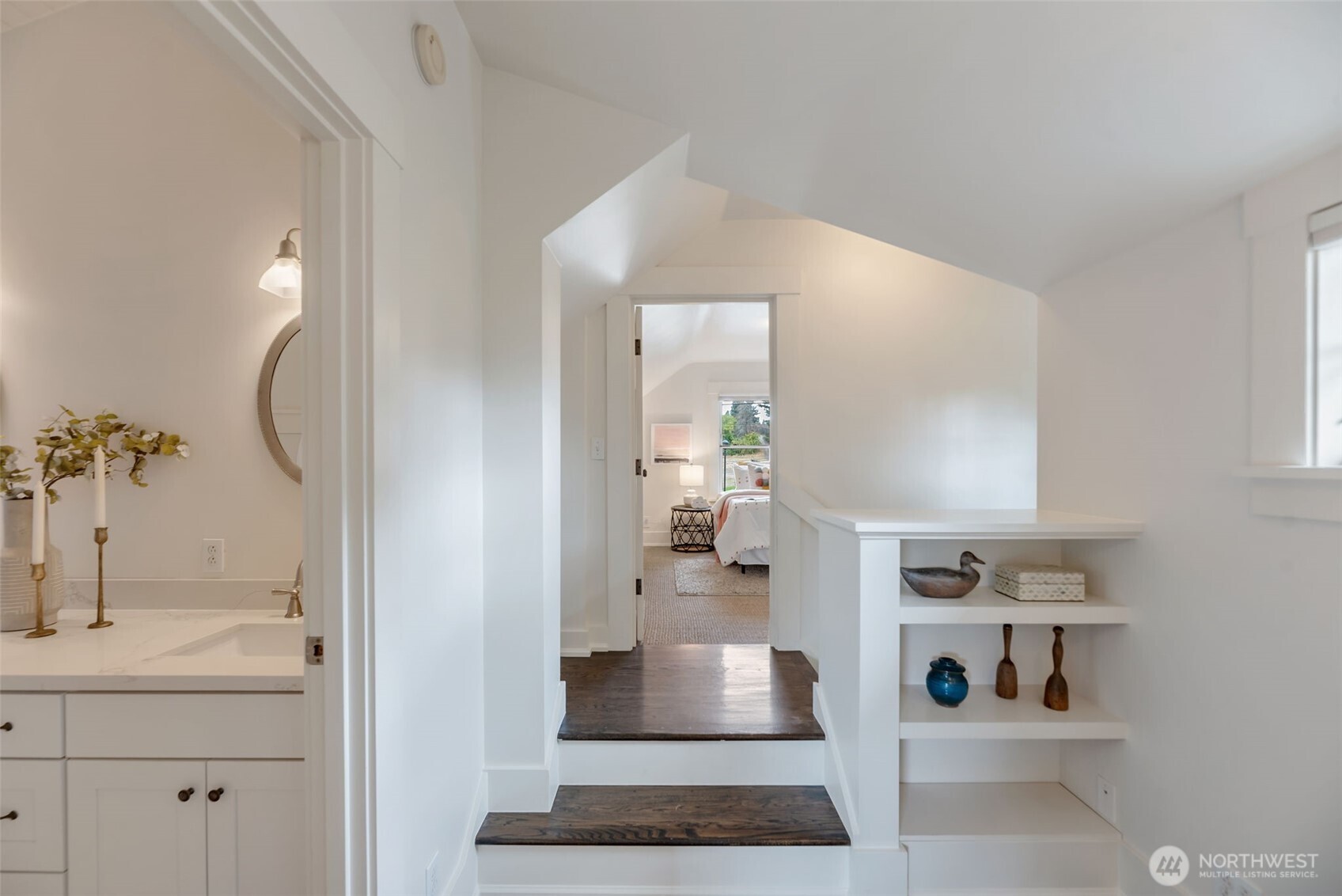 Upstairs hallway with dark wood steps, built-in shelves, and a bedroom visible through the doorway.