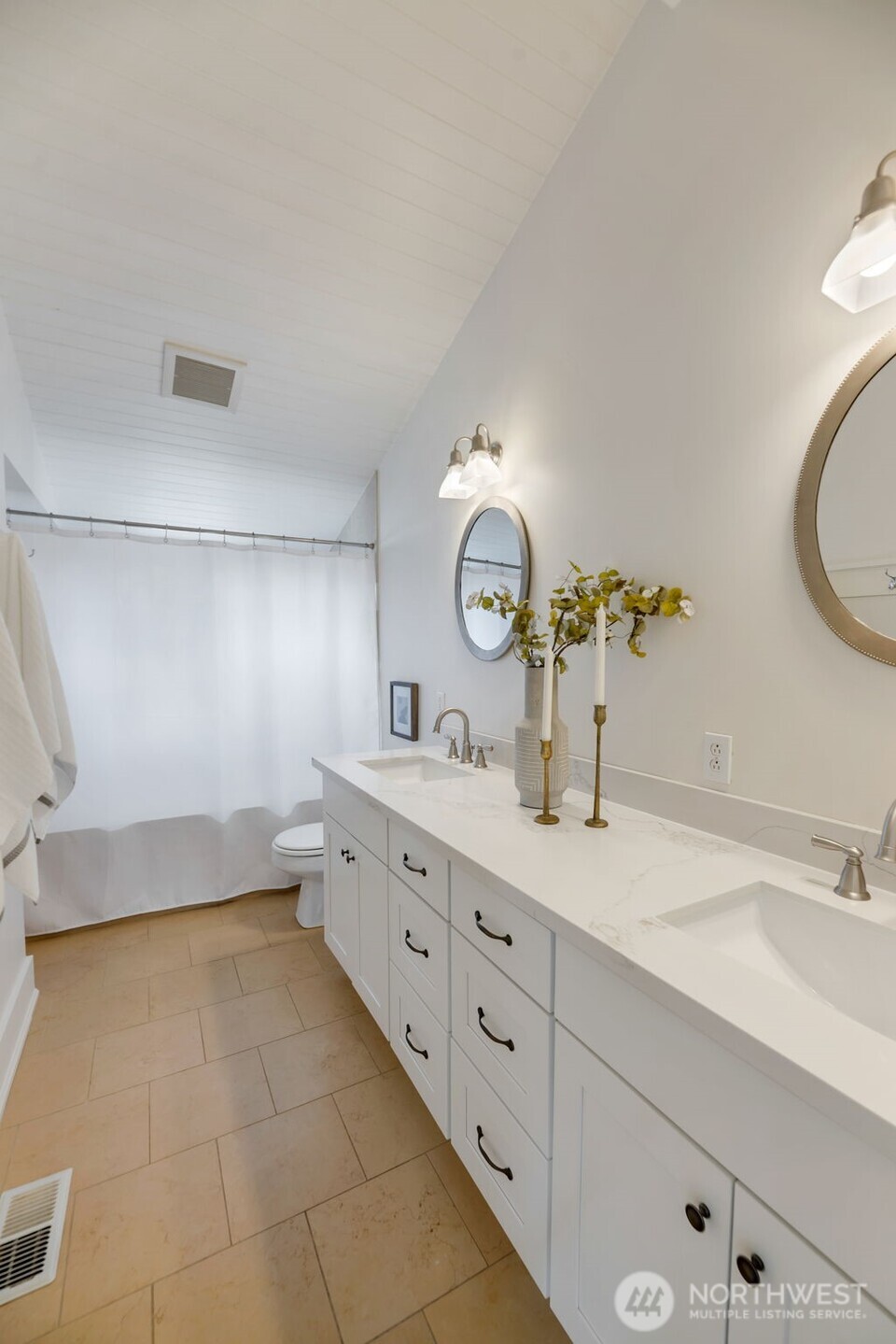 Bathroom with a long white double-sink vanity, marble-look countertop, and tan tile floor.