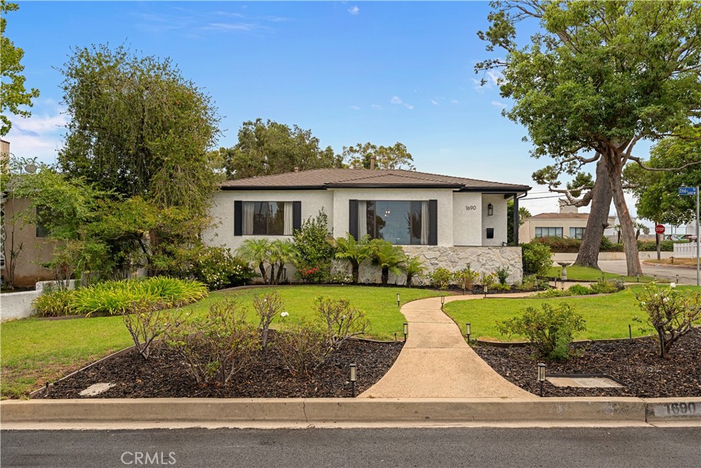 Single-story stucco home with a stone facade and curved front walkway through a landscaped yard.