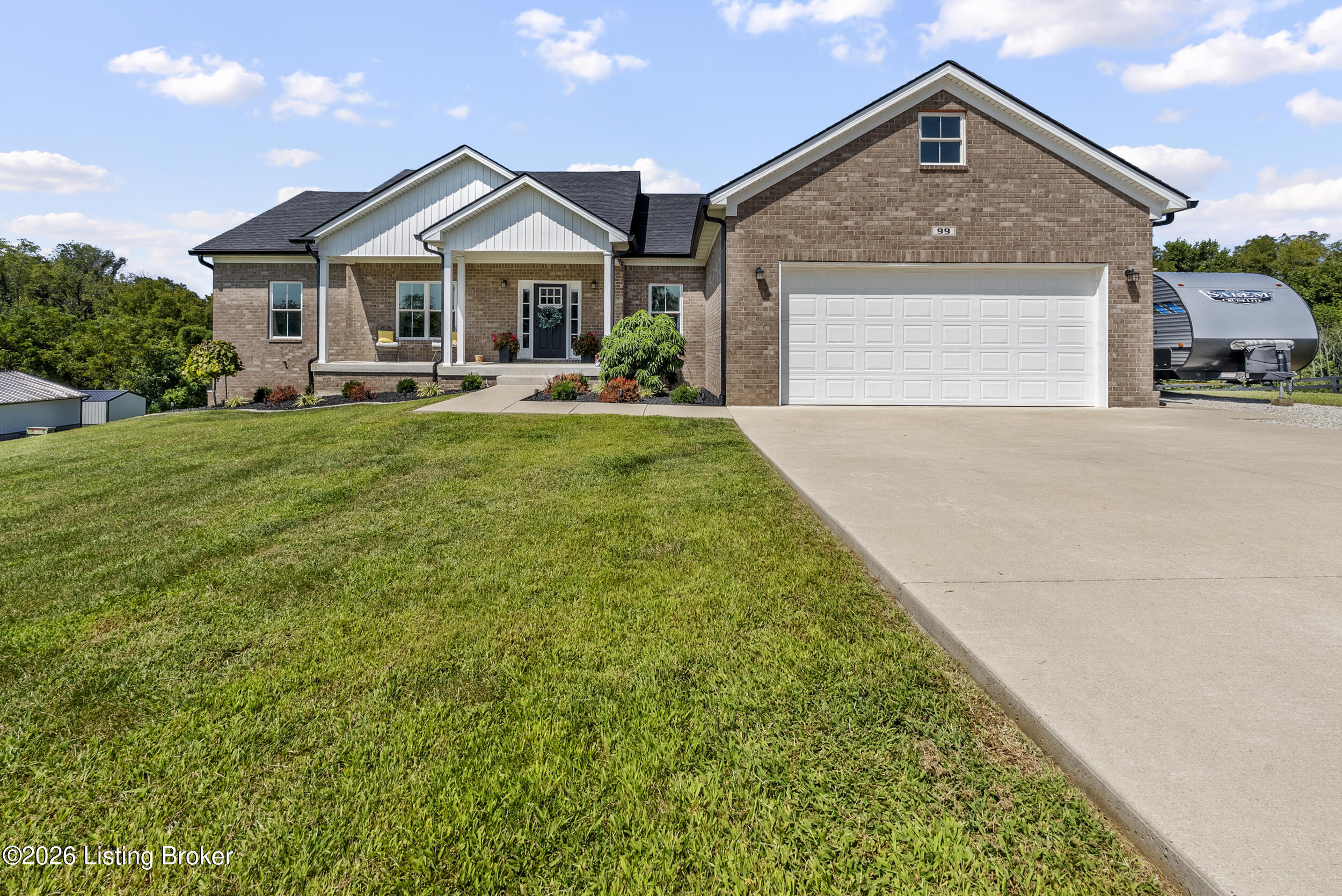 Brick house with a white garage, covered porch, landscaped entry, and broad lawn.