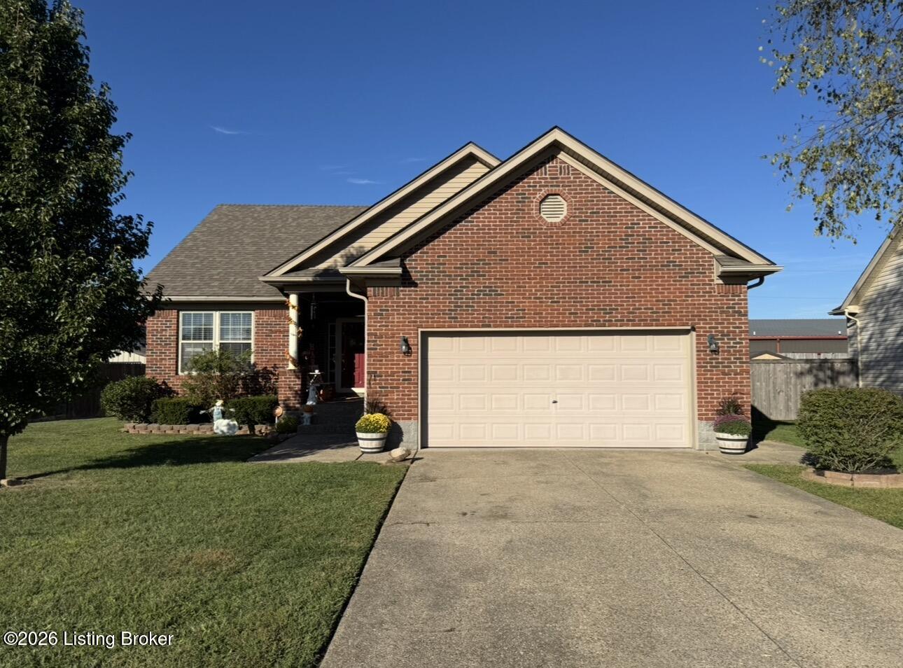 Red brick home with a two-car garage, wide driveway, and landscaped front lawn.