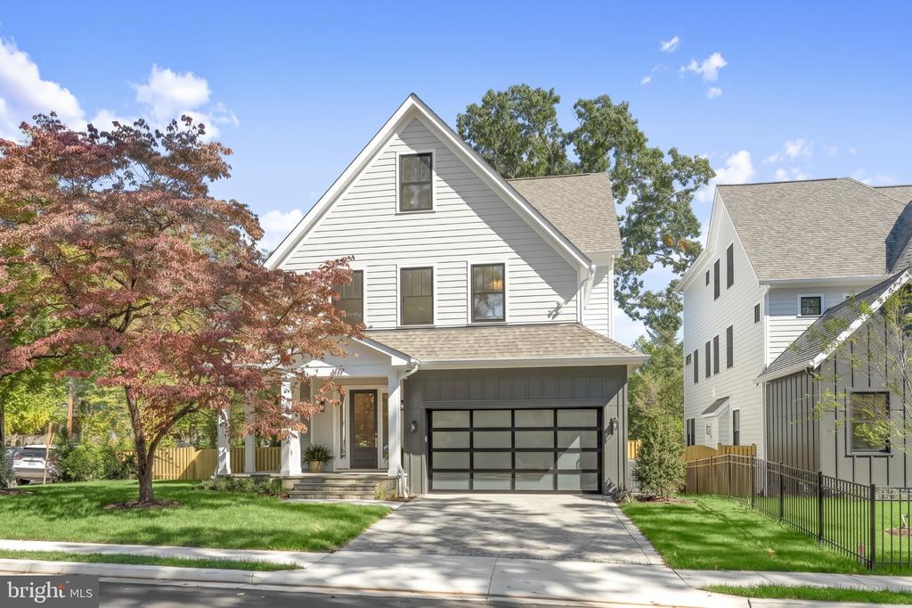 White two-story home with a steep gable, covered porch, and dark garage door.