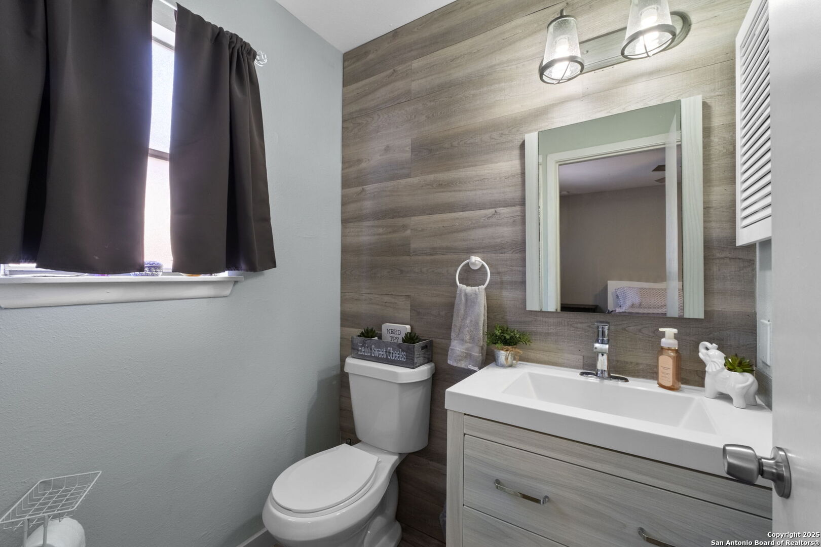 Bathroom with a gray wood-look vanity, white toilet, and wood-look accent wall.