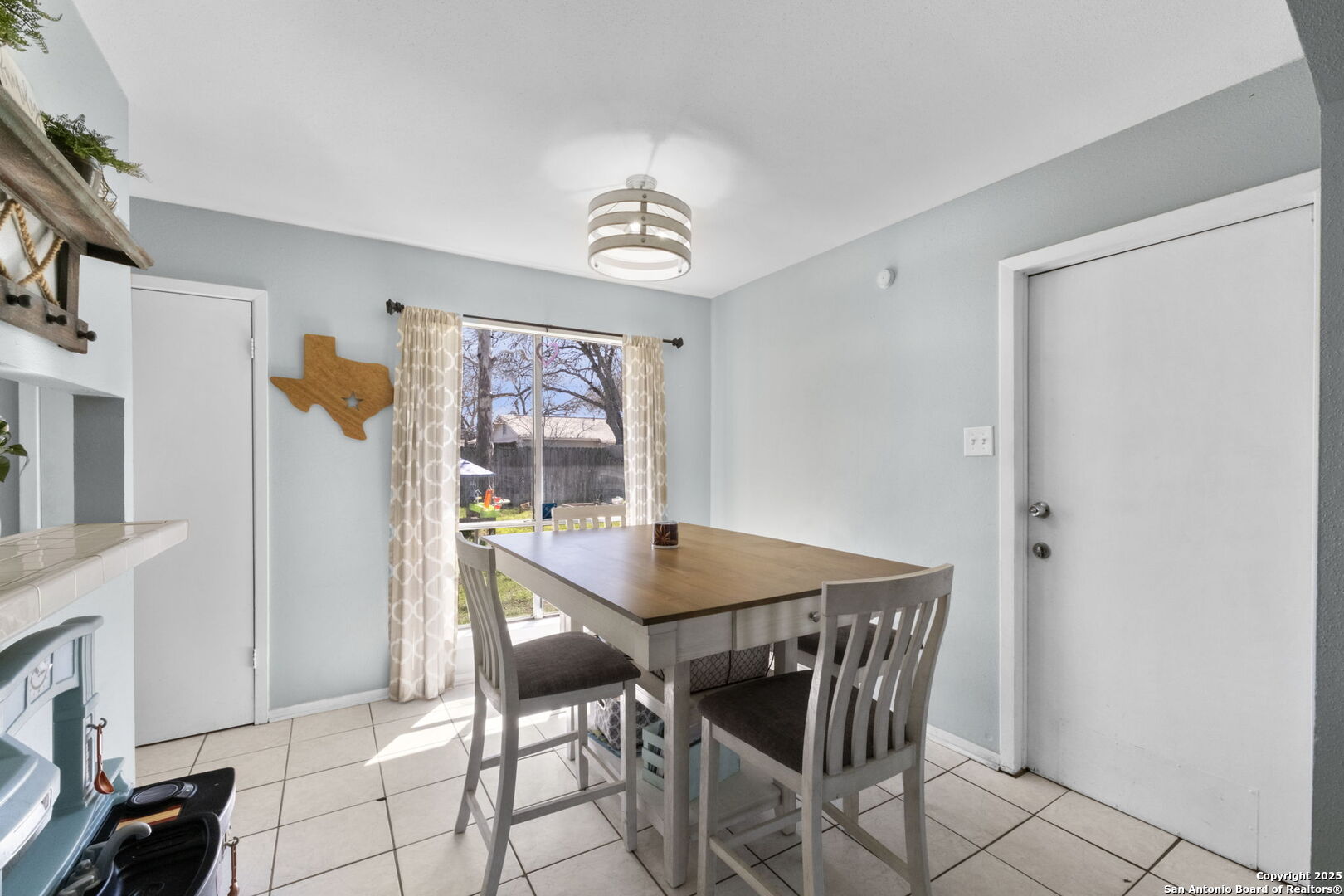 Dining room with a wooden table and gray chairs beside a sunlit window.
