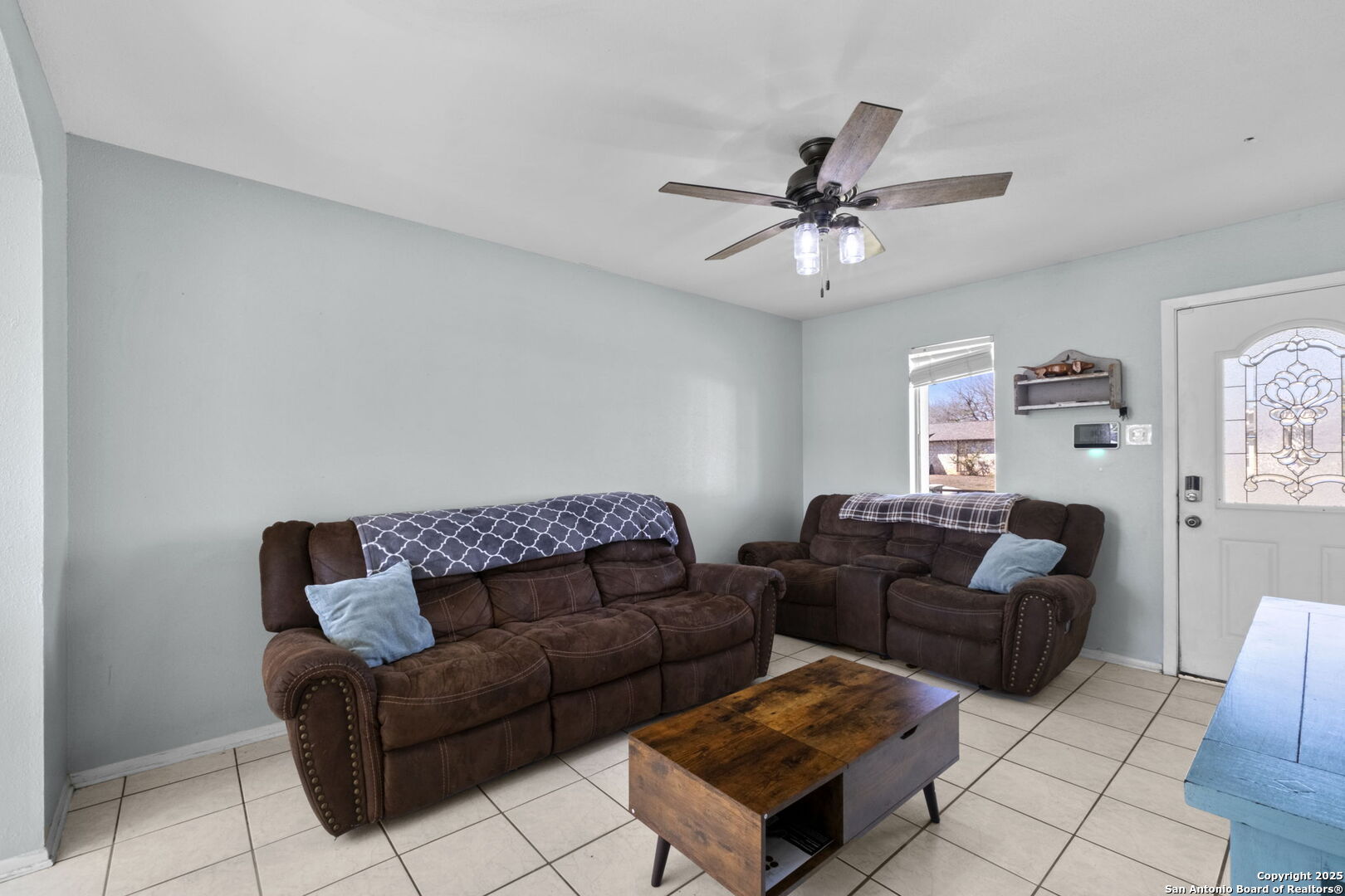 Living room with brown reclining sofas, tiled floors, and a wooden coffee table.