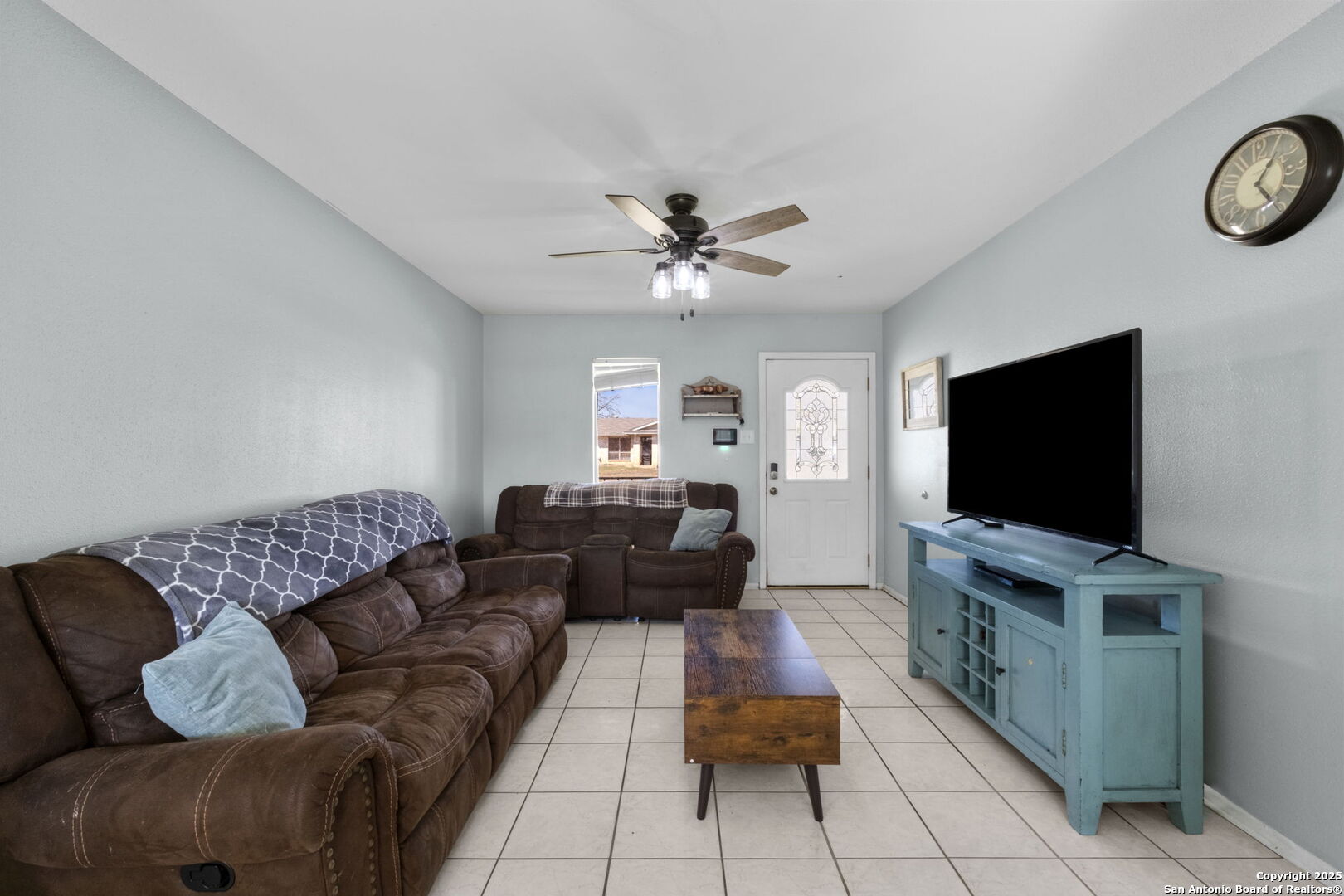 Living room with brown reclining sofas, a wood coffee table, and a television on a turquoise console.
